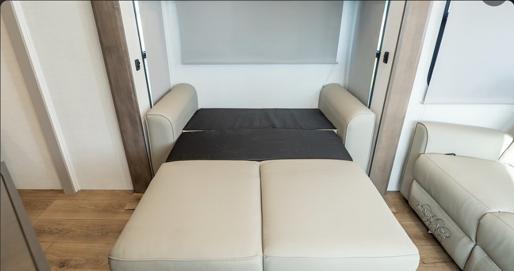 This RV rental features a comfortable, space-saving pull-out sofa bed with beige cushions and a dark gray mattress.. Alliance RV Avenue 2025