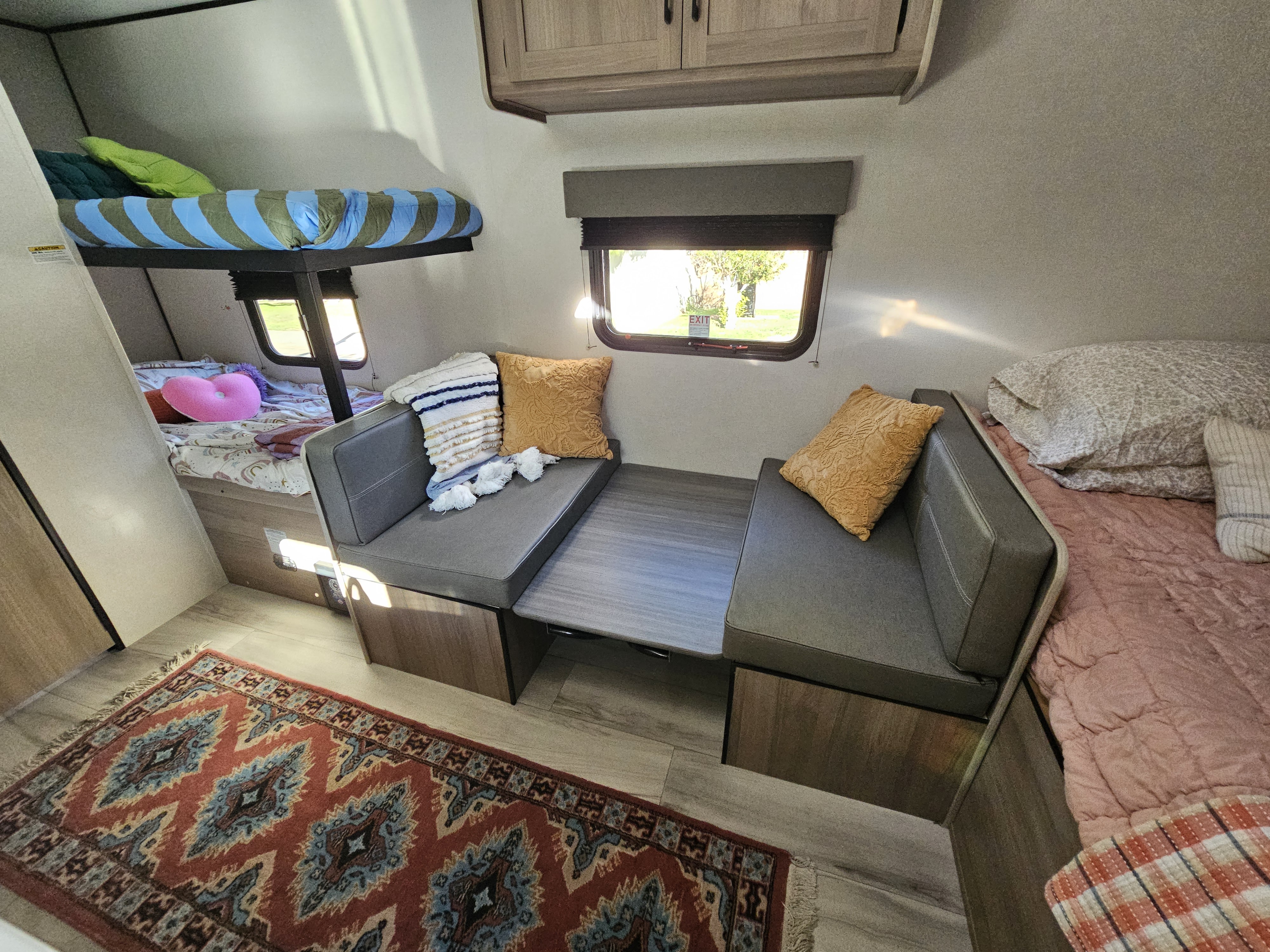 Cozy RV rental interior featuring bunk beds, a dinette, and a main sleeping area with a colorful rug.. Keystone Coleman 17BX 2025