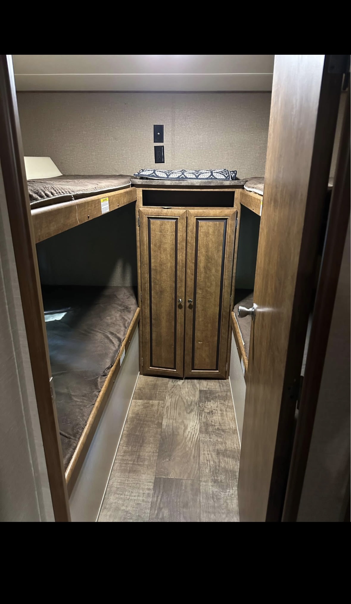 Cozy RV rental bunk room featuring stacked beds on both sides, a central storage cabinet, and wood-look flooring.. Crossroads RV Z-1 2017