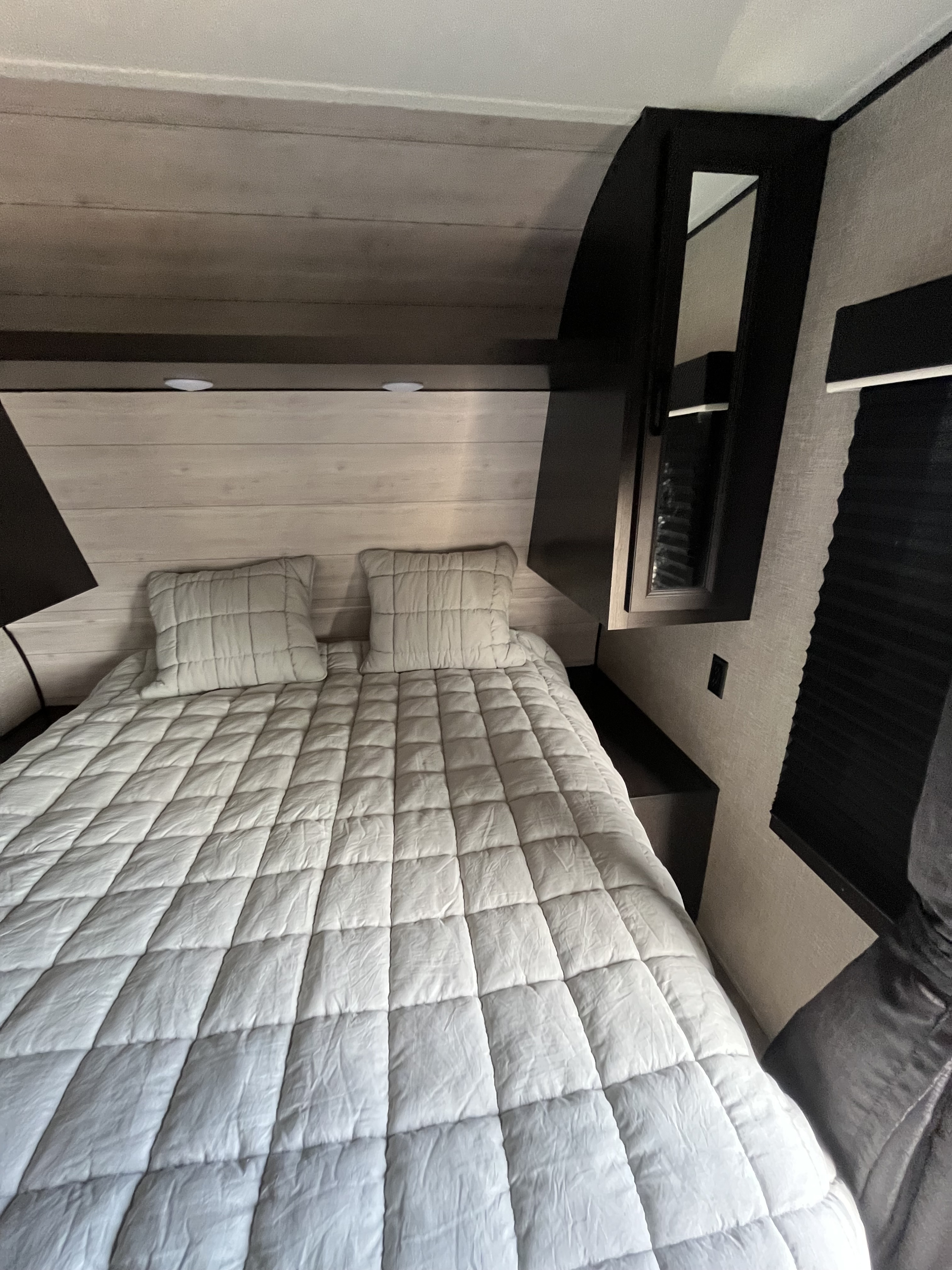 Cozy RV rental bedroom featuring a queen bed with a light grey quilted comforter and modern built-in storage.. Jayco Jay Flight SLX Rocky Mountain Edition 2022