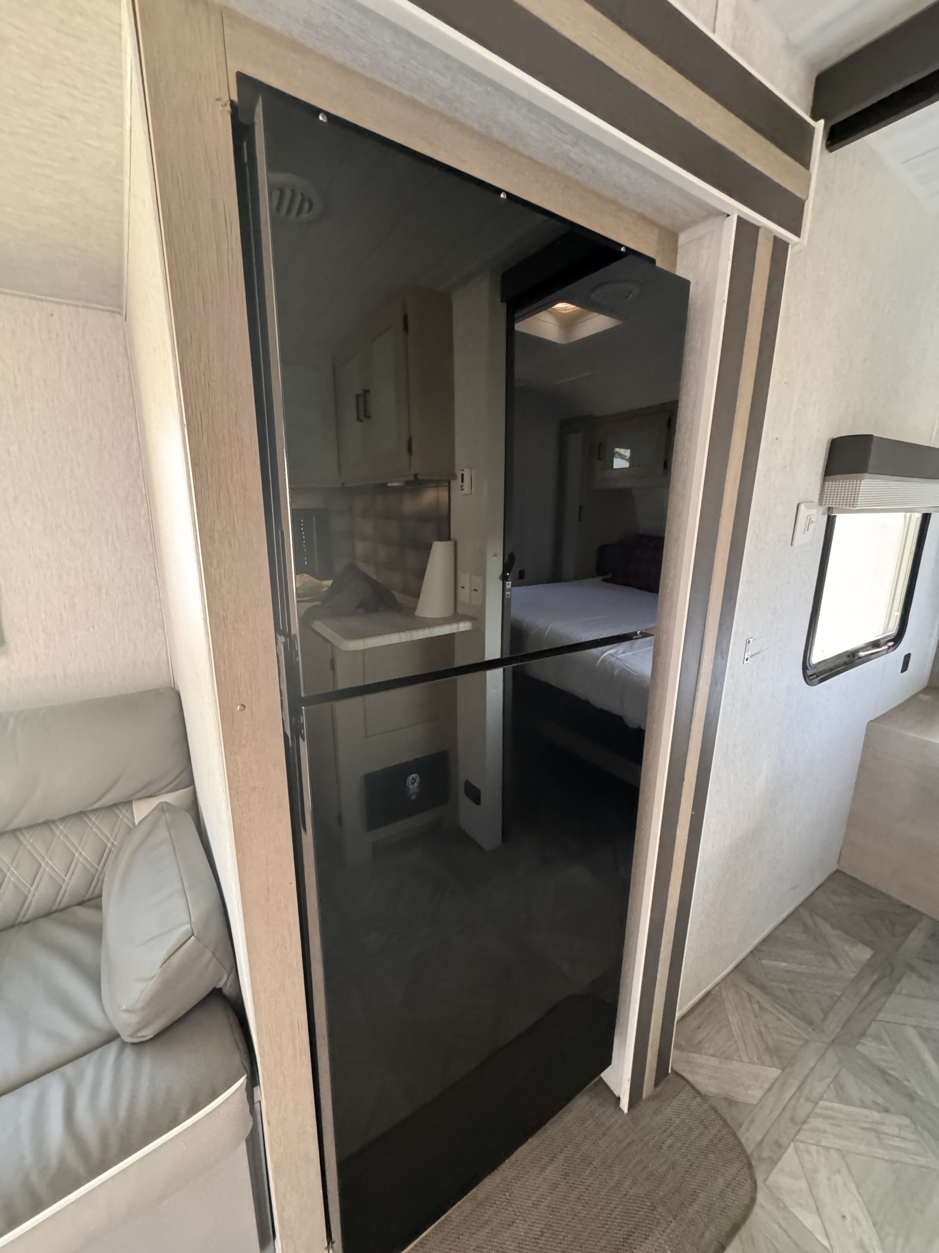 Modern RV rental interior, revealing the bedroom, kitchen, and living area through a sleek, dark sliding door.. Forest River Wildwood 2023