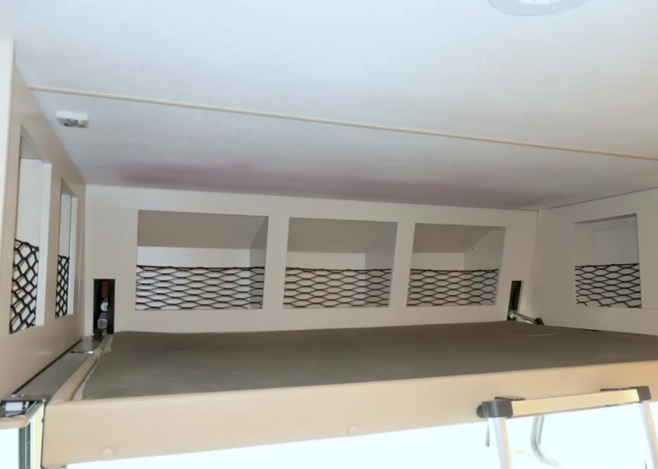 Overhead bunk bed with mesh storage cubbies in an RV rental interior, offering practical sleeping and space.. Thor A.C.E. 2022