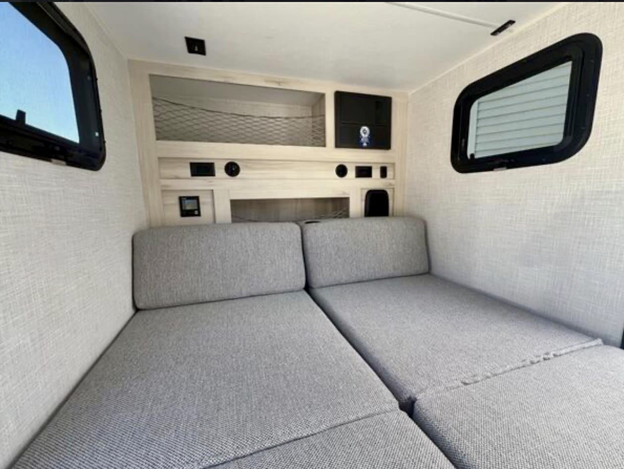 RV rental interior with two twin-style beds, overhead storage, and side windows. Compact and functional.. Bontrager Outdoors 12RAD 2025
