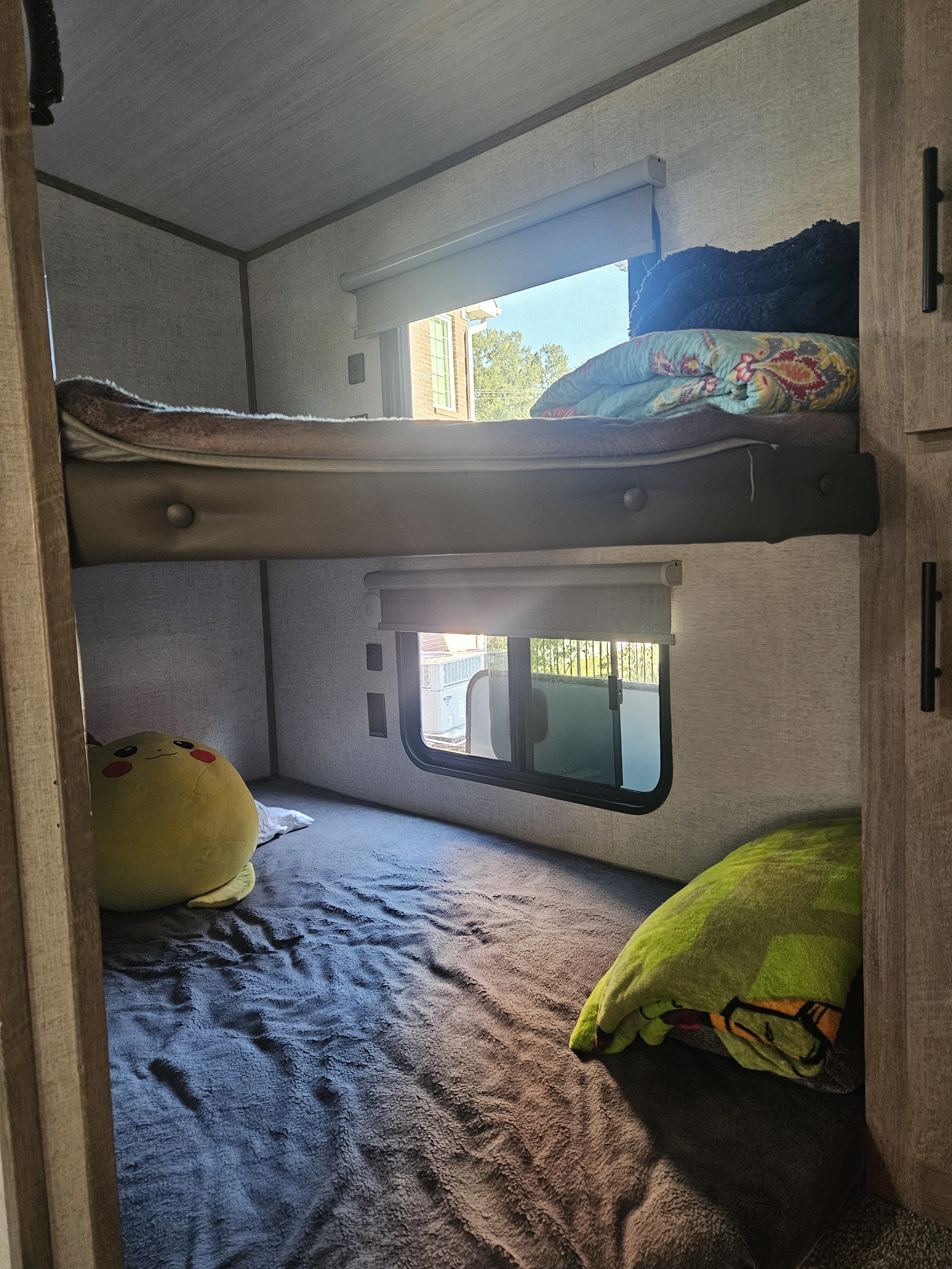Cozy bunk beds in an RV rental, featuring windows, blankets, and a plush toy for a comfortable sleeping area.. Forest River Salem Hemisphere 2021