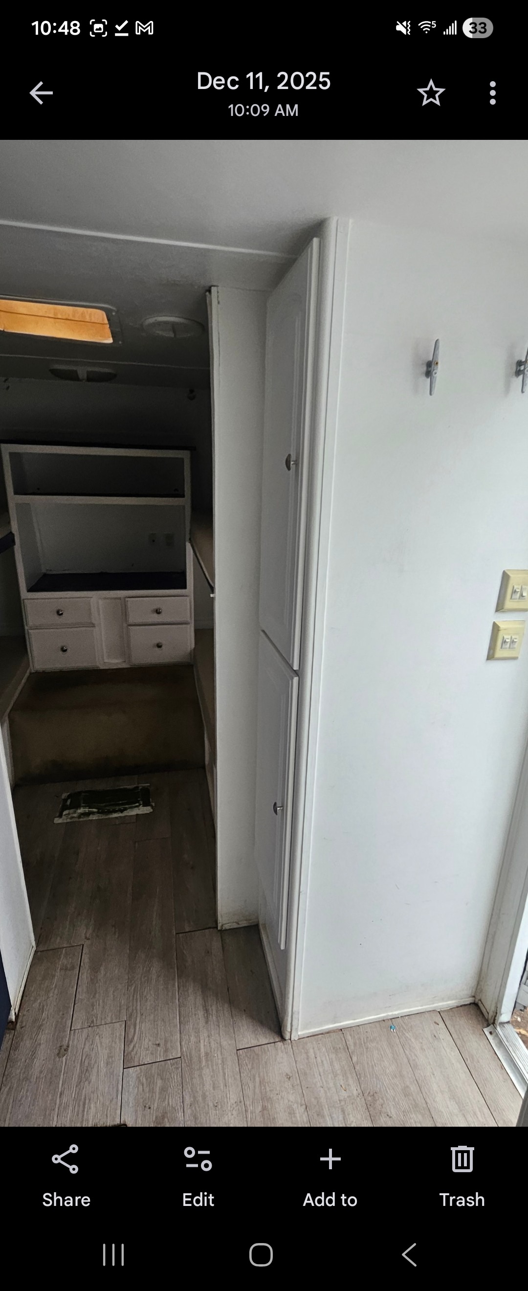 RV rental interior: A narrow hallway with light wood-look flooring, a built-in cabinet, and white walls with hooks & switches.. Keystone RV Outback 2005