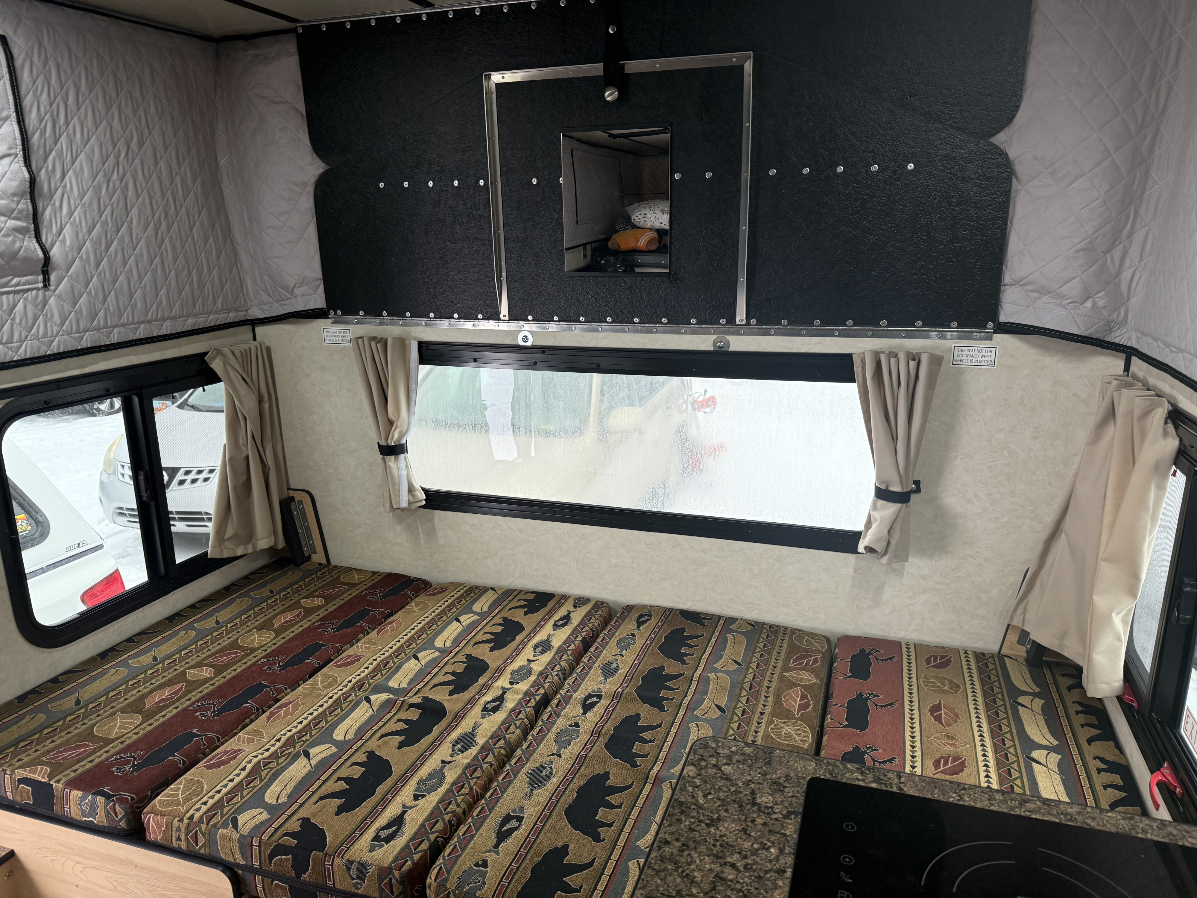 Inside an RV rental: nature-patterned cushions, pop-top walls, and a window for scenic camping views.. Four Wheel Campers Hawk + 2026