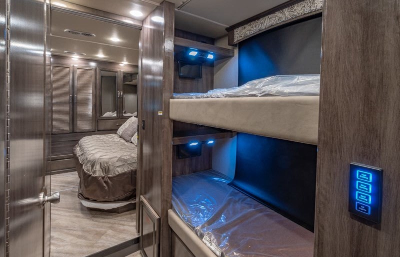 Inside this modern RV rental, discover comfortable bunk beds with blue accent lighting and a separate master bedroom. Ideal for family trips.. Fleetwood Pace Arrow 35E 2019