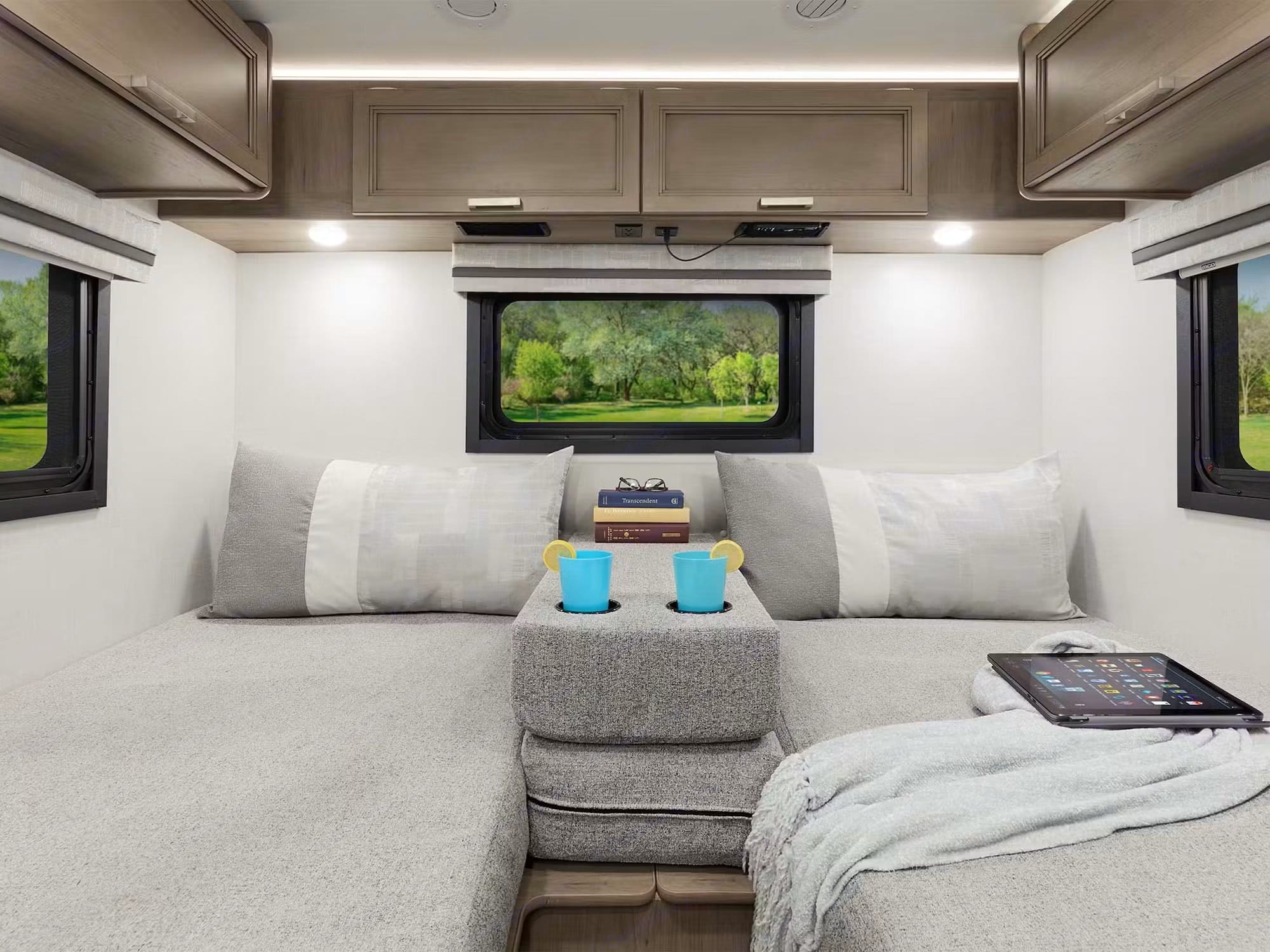 Cozy RV rental interior: convertible beds, overhead storage, a nature view, and relaxation amenities like drinks & tablet.. Axis 24.1 2026