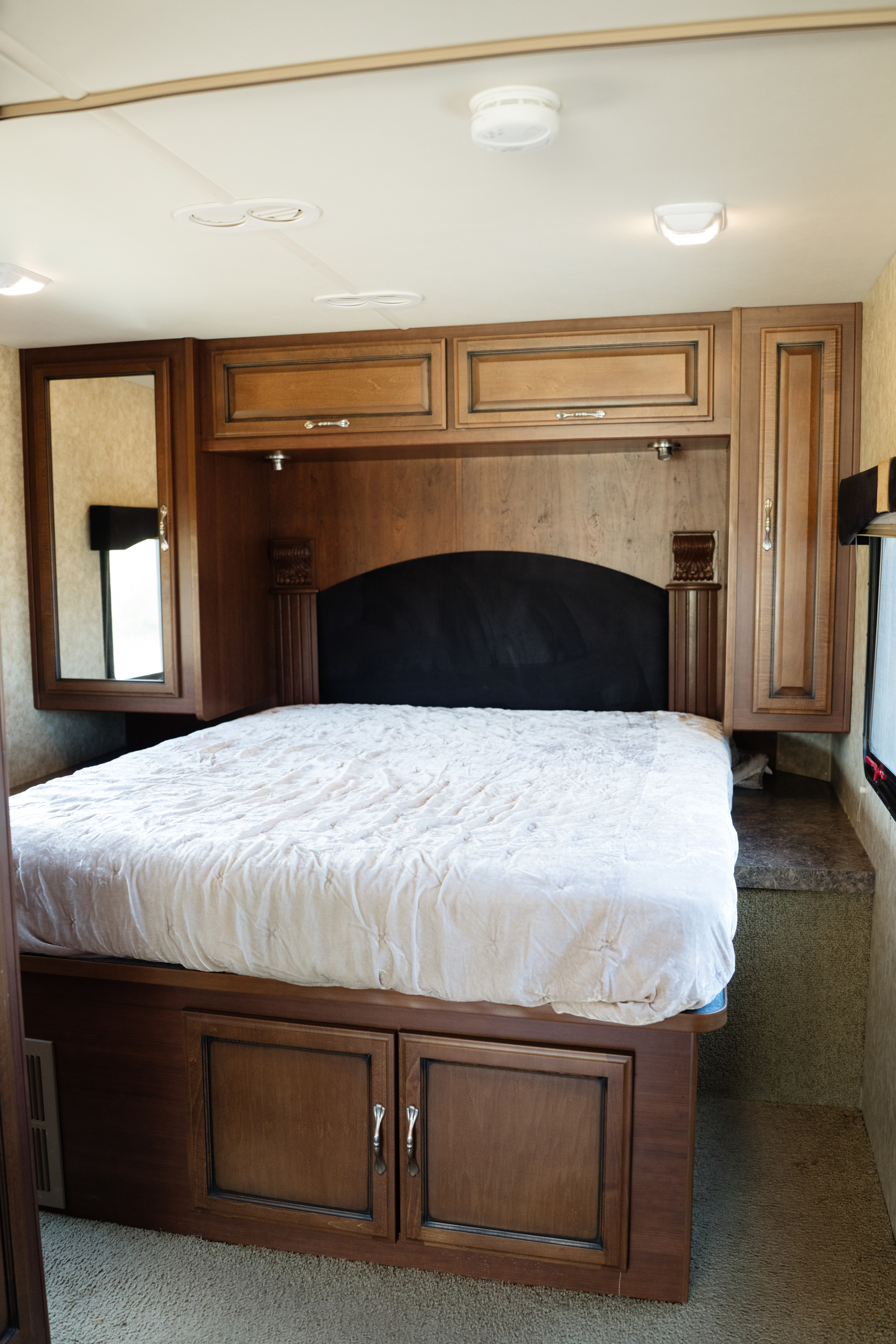Comfortable RV rental bedroom with wooden cabinetry, a plush bed, and cozy lighting for your next adventure.. Fleetwood Other 2012