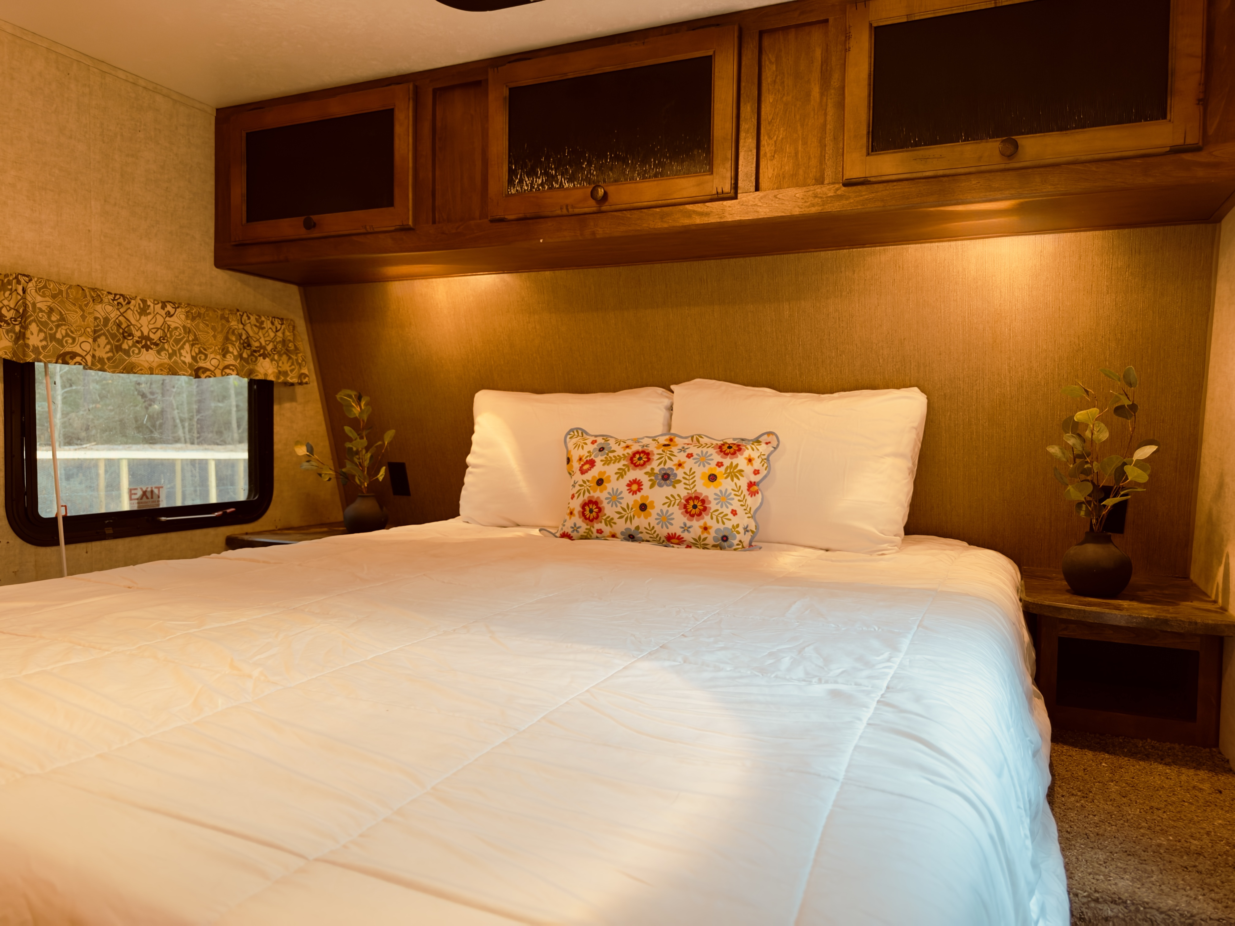 Inviting RV rental bedroom with a comfy bed, warm lighting, window view, & practical overhead storage.. Keystone RV SPRINTER 2014