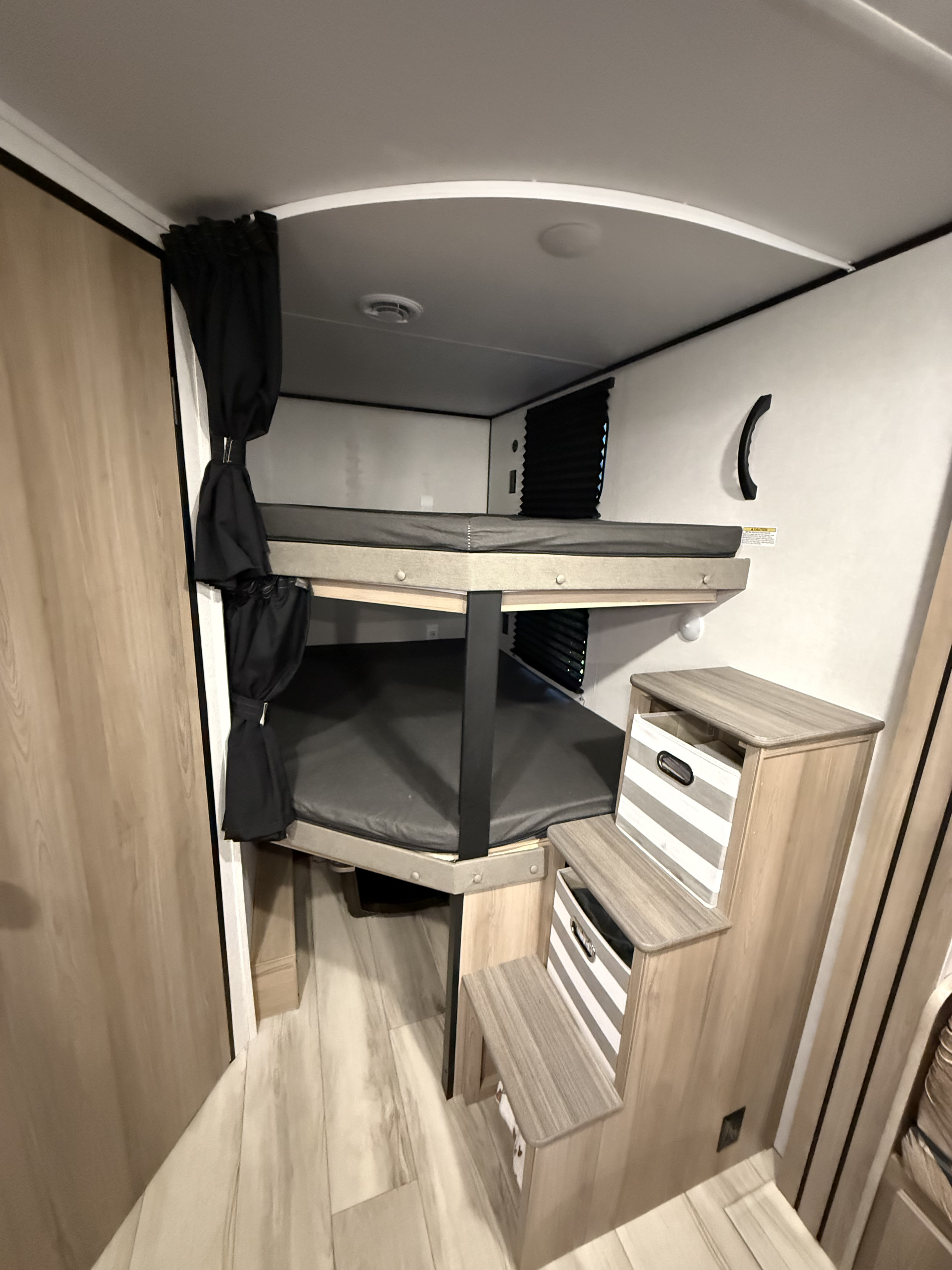 This RV rental features modern bunk beds with privacy curtains and storage steps, designed for comfortable travel.. Keystone RV Coleman Lantern 2025