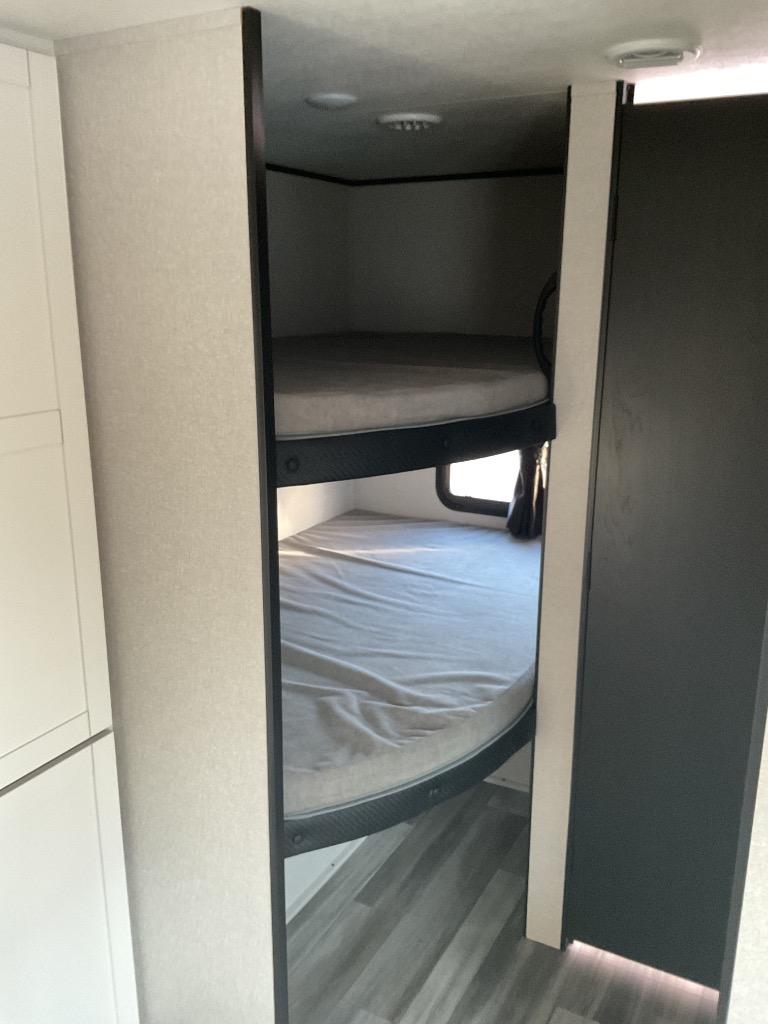Cozy bunk beds inside an RV rental, featuring a two-tier sleeping area with light walls and dark trim for travelers.. Jayco Jayflight 261BHS 2026
