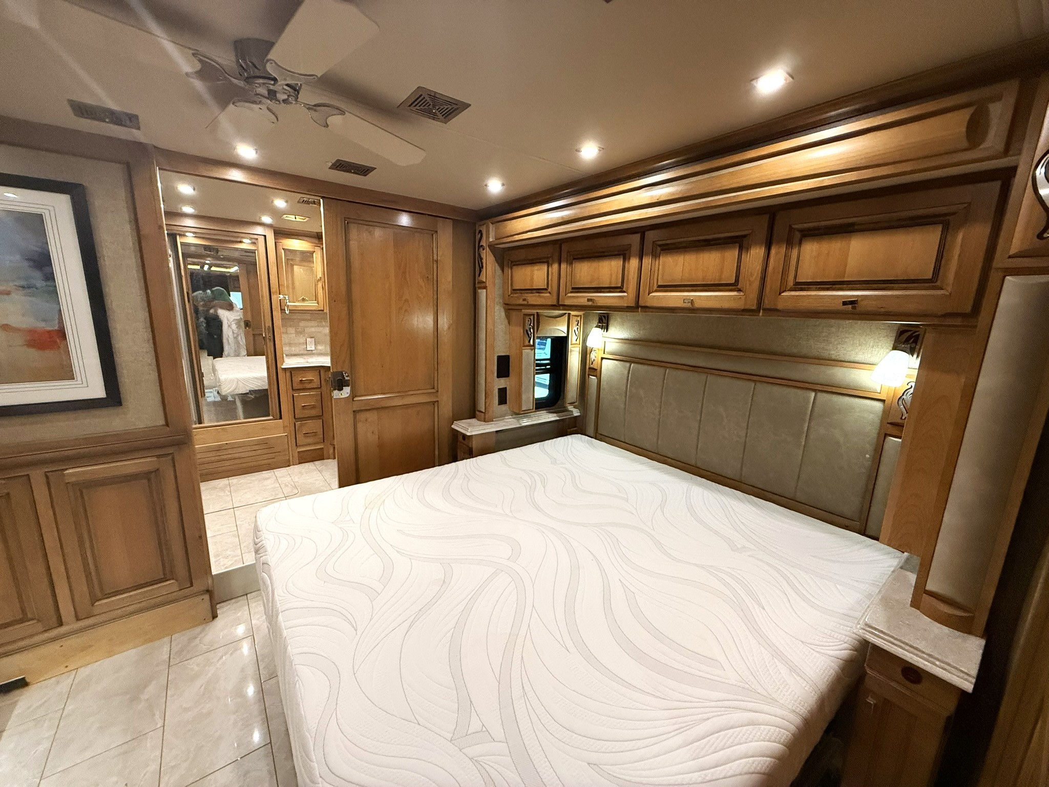 Cozy RV rental bedroom showcasing a plush bed, warm wooden cabinets, and bright lighting. Perfect for your next adventure.. Tiffin Phaeton 2020