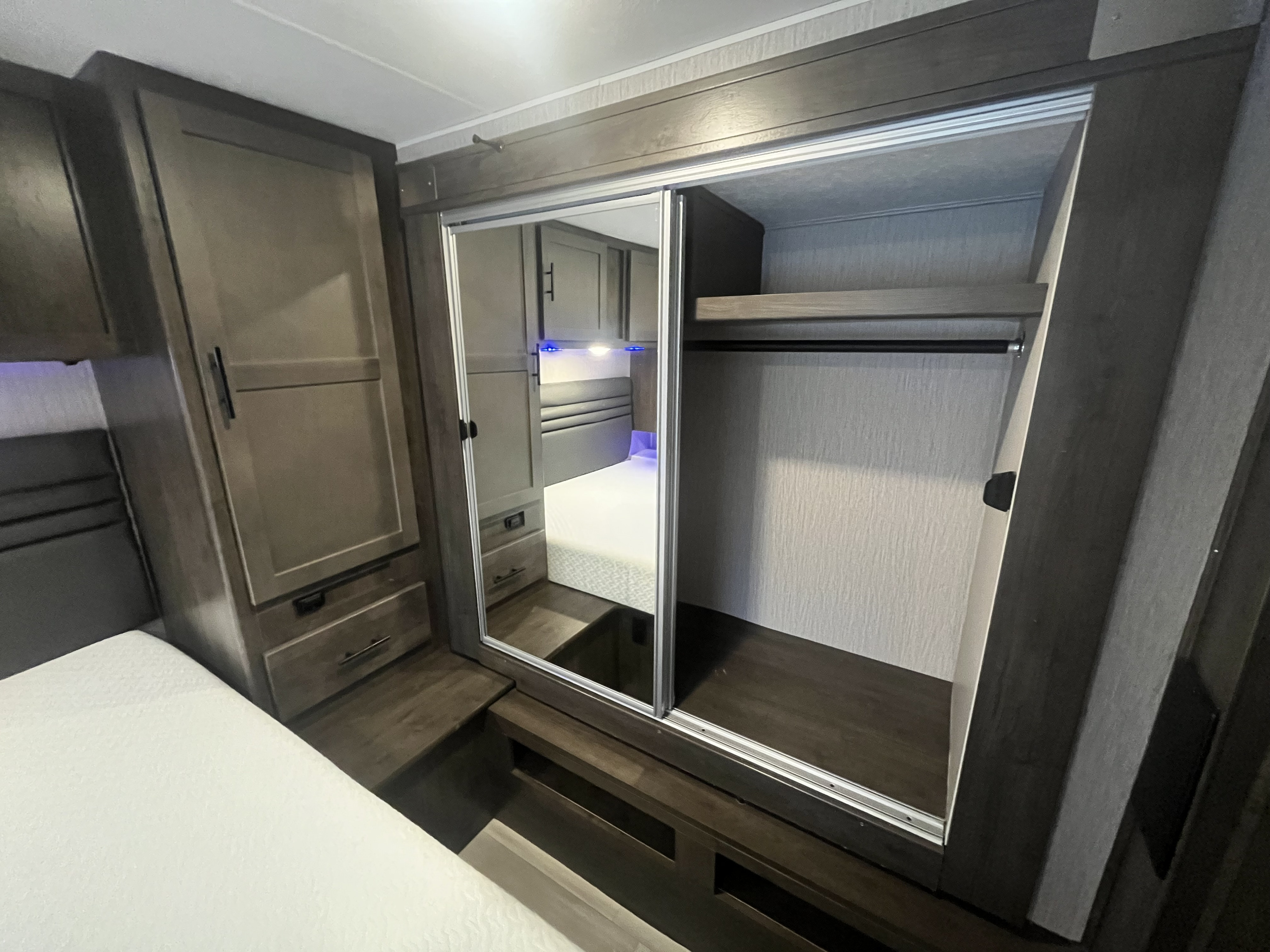 RV rental bedroom with a large mirrored sliding closet, ample storage, and a comfortable bed.. Coachmen Leprechaun 2022