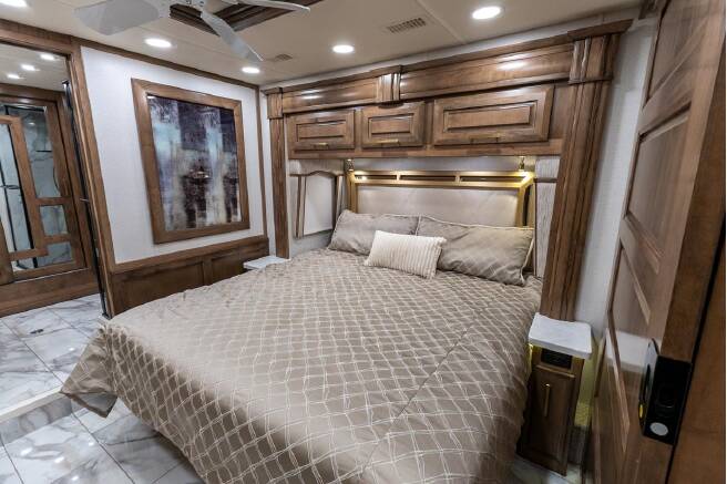 Comfortable and well-appointed RV rental bedroom with a large bed, overhead wooden cabinetry, and modern interior design.. Entegra Coach Cornerstone 2022