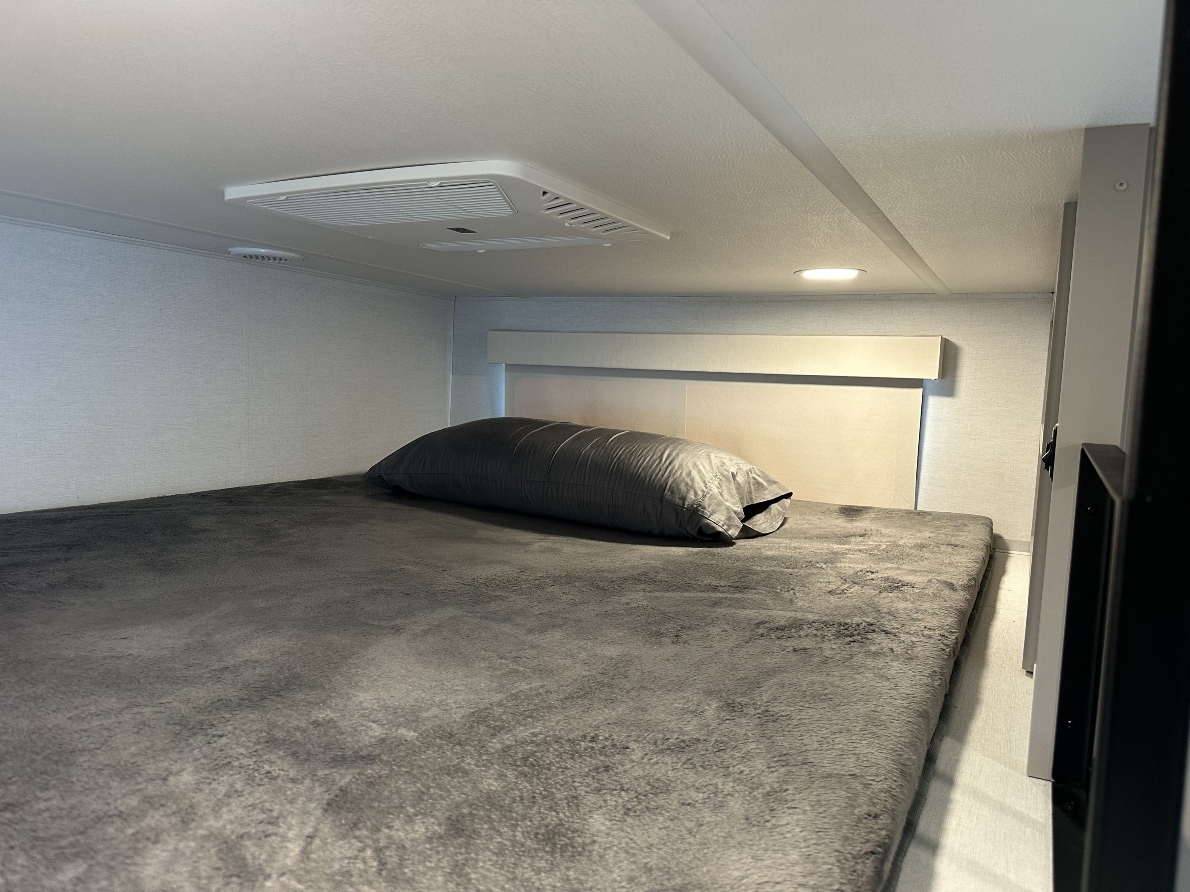Cozy rv rental sleeping area with gray bedding, air conditioning, and a headboard light. Perfect for travel.. Alliance RV Paradigm 2025