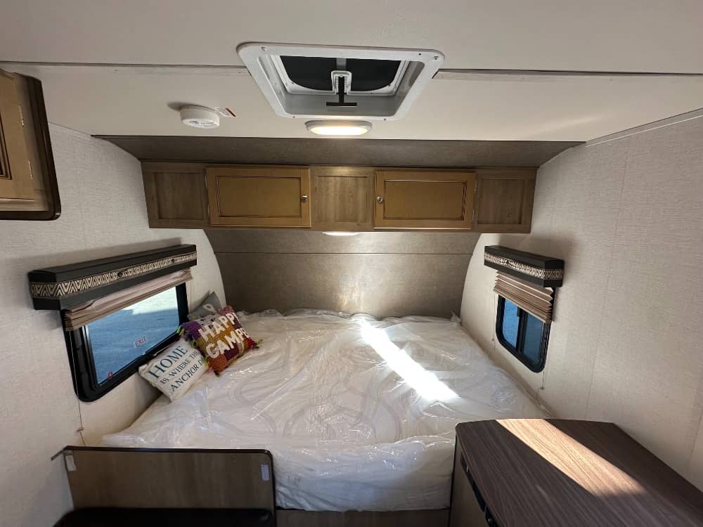 Cozy RV rental bedroom featuring a bed, overhead storage, windows, and ceiling vent, ready for your next camping adventure.. Palomino Real Lite Mini 2017