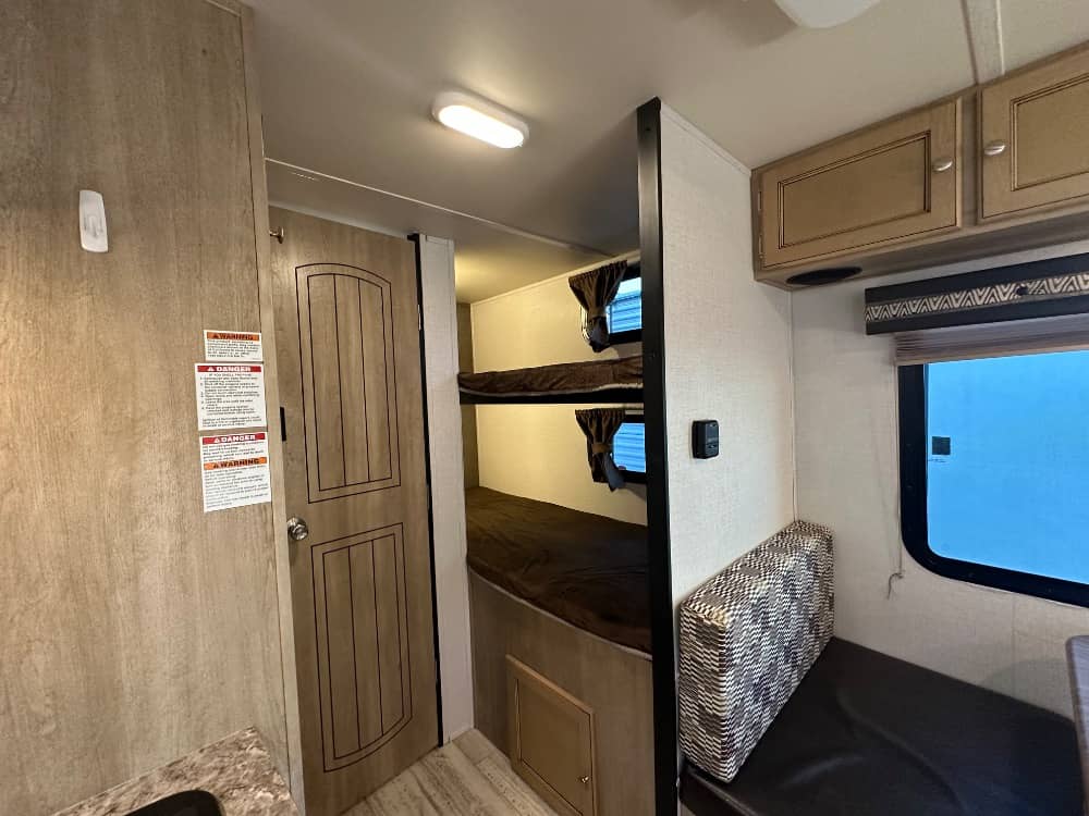 RV rental interior features bunk beds, a small dinette with a window, and overhead cabinets for family trips.. Palomino Real Lite Mini 2017