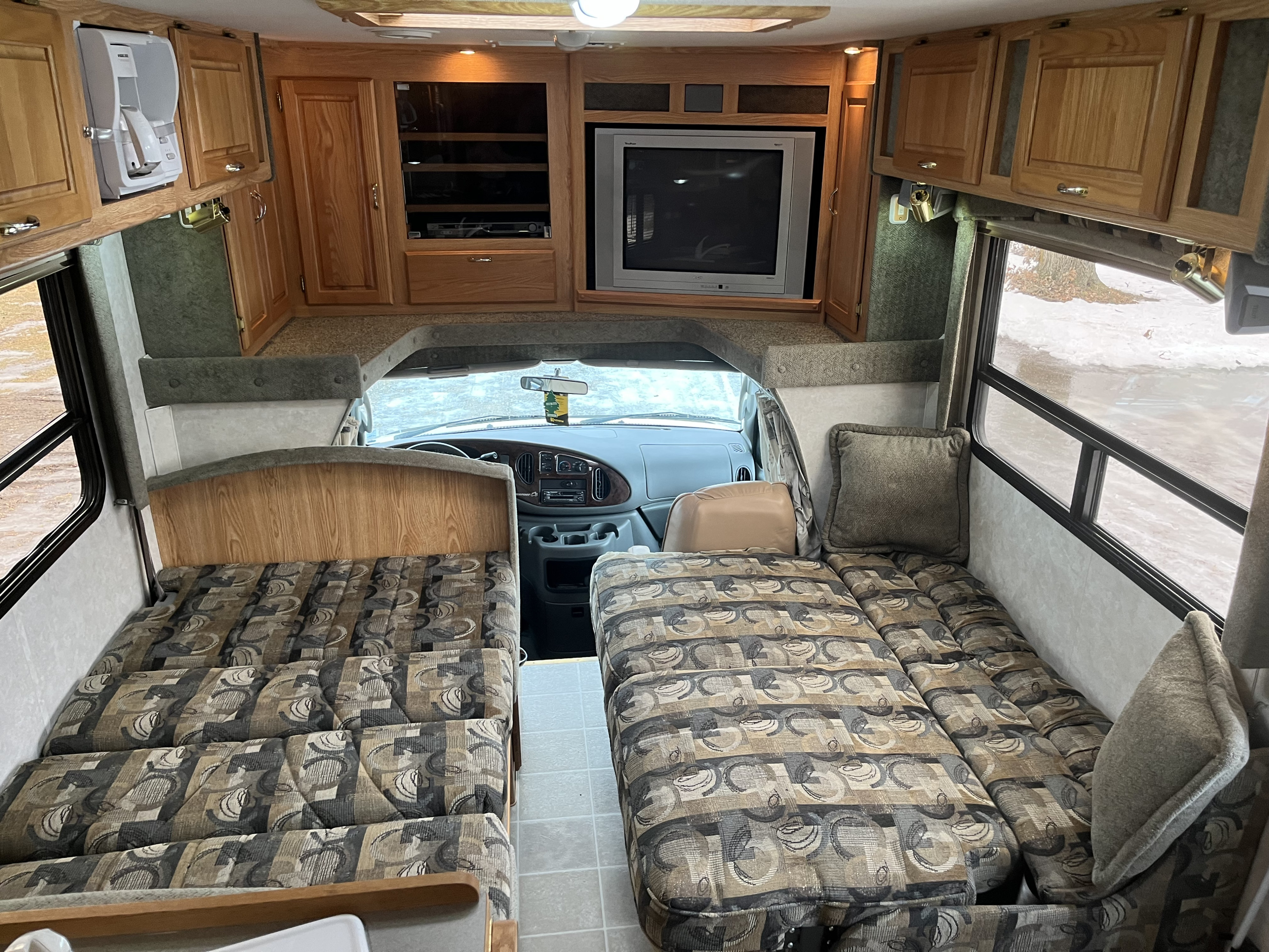 Spacious RV rental interior featuring convertible sleeping areas, a TV, kitchenette, and driver's cabin upfront.. Bigfoot RV Bigfoot RV Motorhome 2004