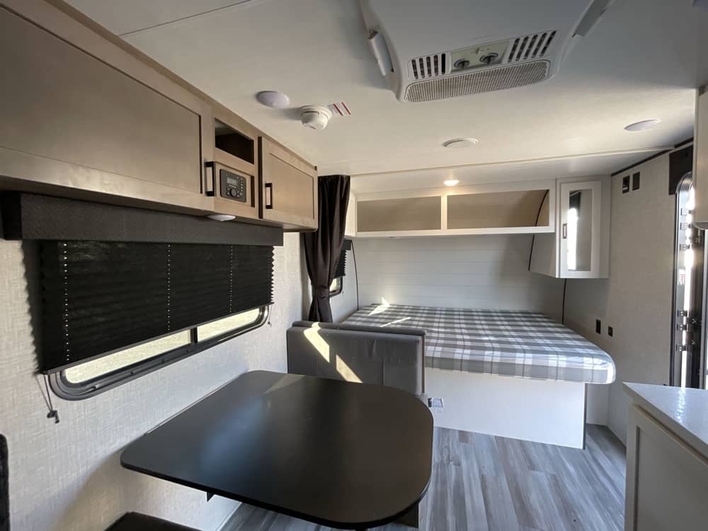 Cozy RV rental interior featuring a plaid bed, dinette, and sleek cabinets, ready for your next getaway.. Jayco Jay Flight SLX 2025