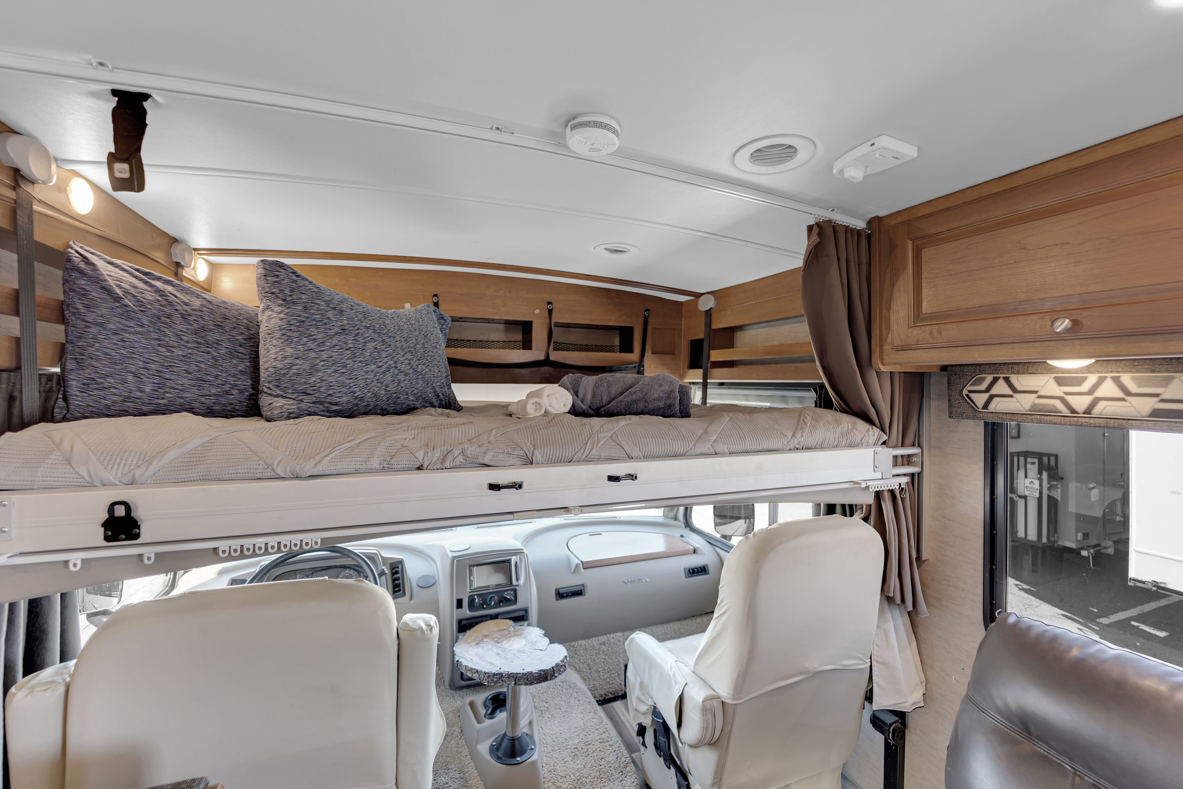 RV rental interior: a cozy over-cab bed sits above the driver's cockpit and passenger seats, ready for adventure.. Winnebago Vista 2017