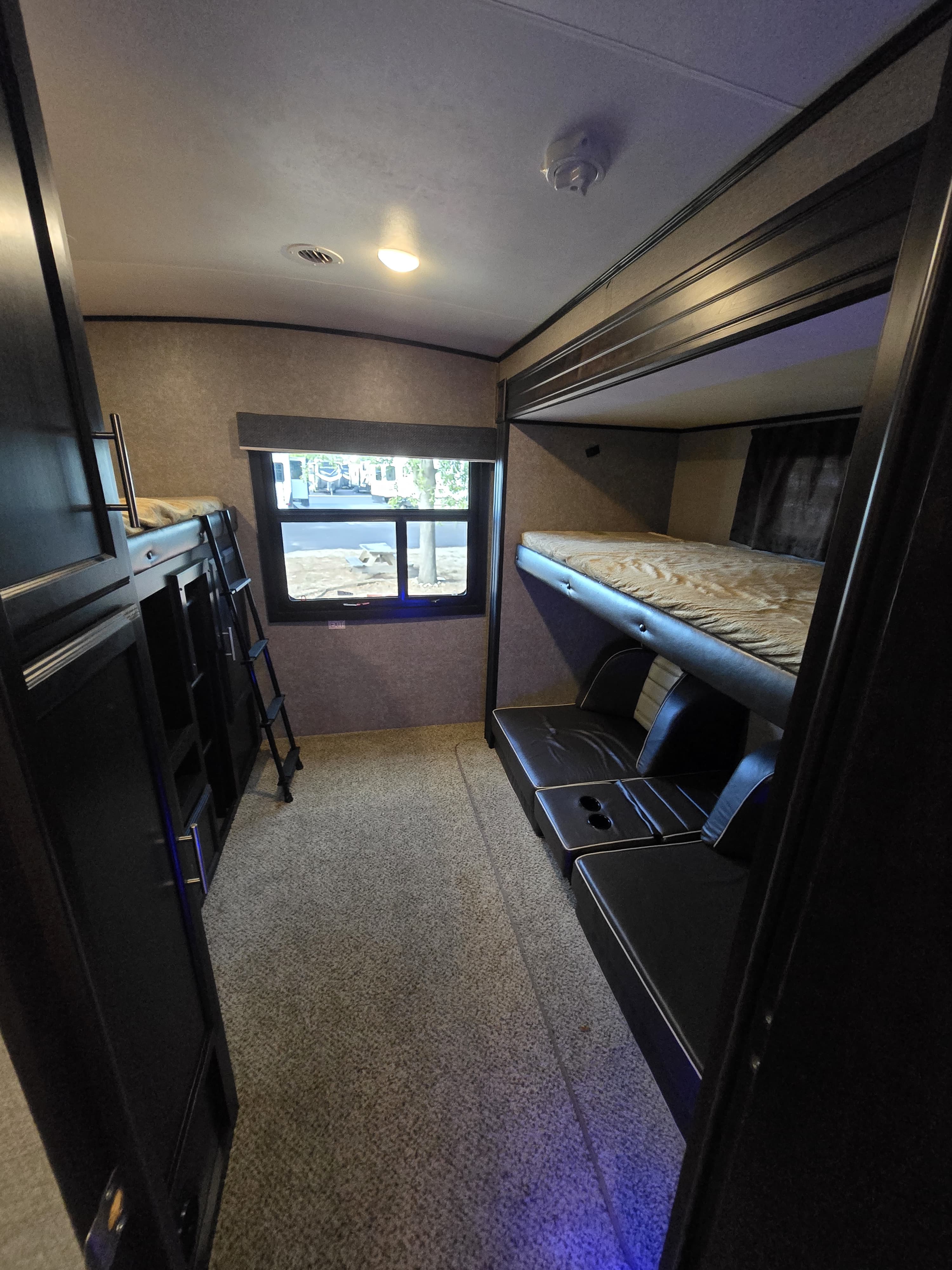 Cozy rv rental bunk room featuring two sets of bunks, lower seating, and a window for natural light.. Jayco Eagle HT 2020