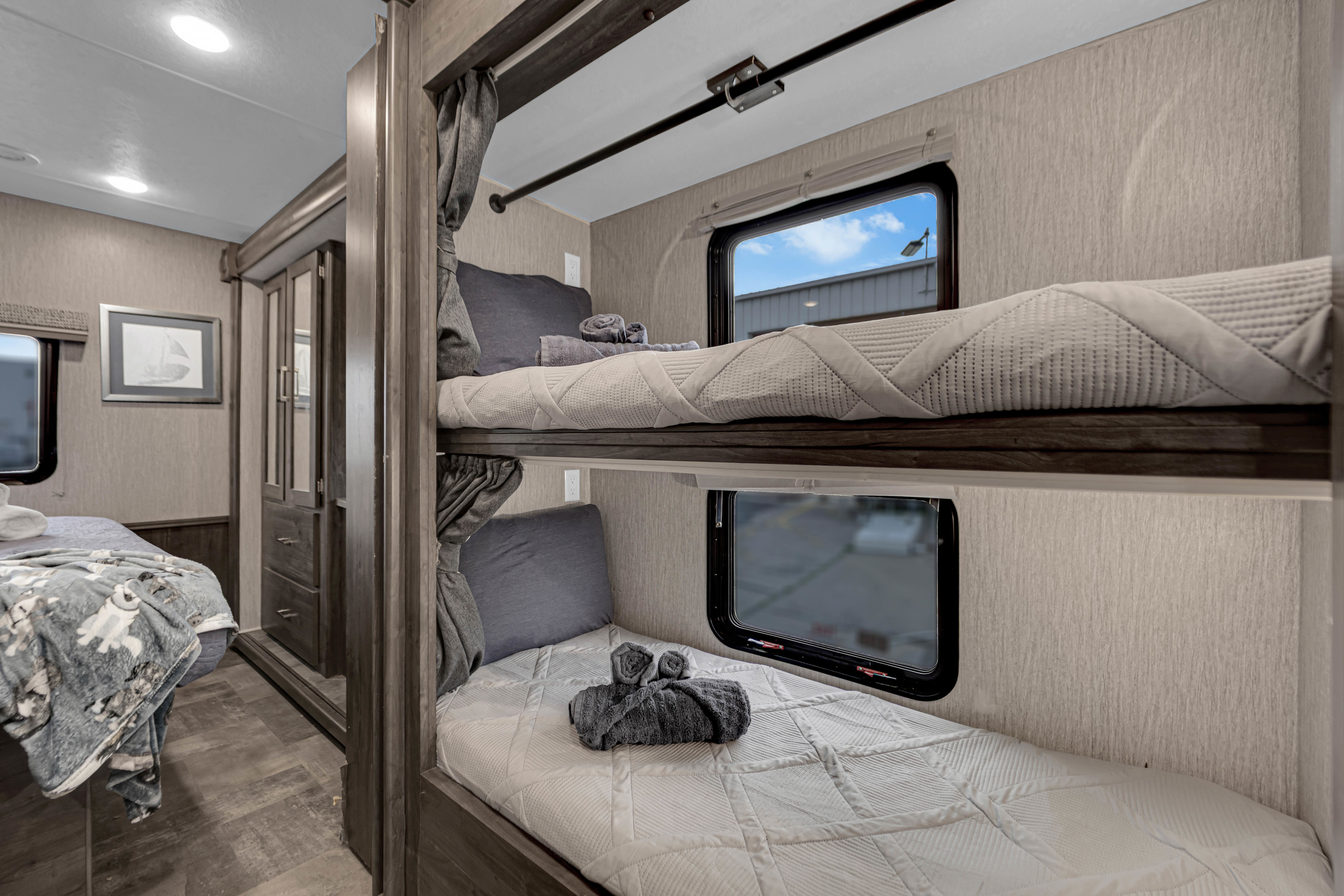 Cozy bunk beds in an RV rental, complete with curtains, windows, and soft bedding for a comfortable journey.. coachmen Pursuit 2022