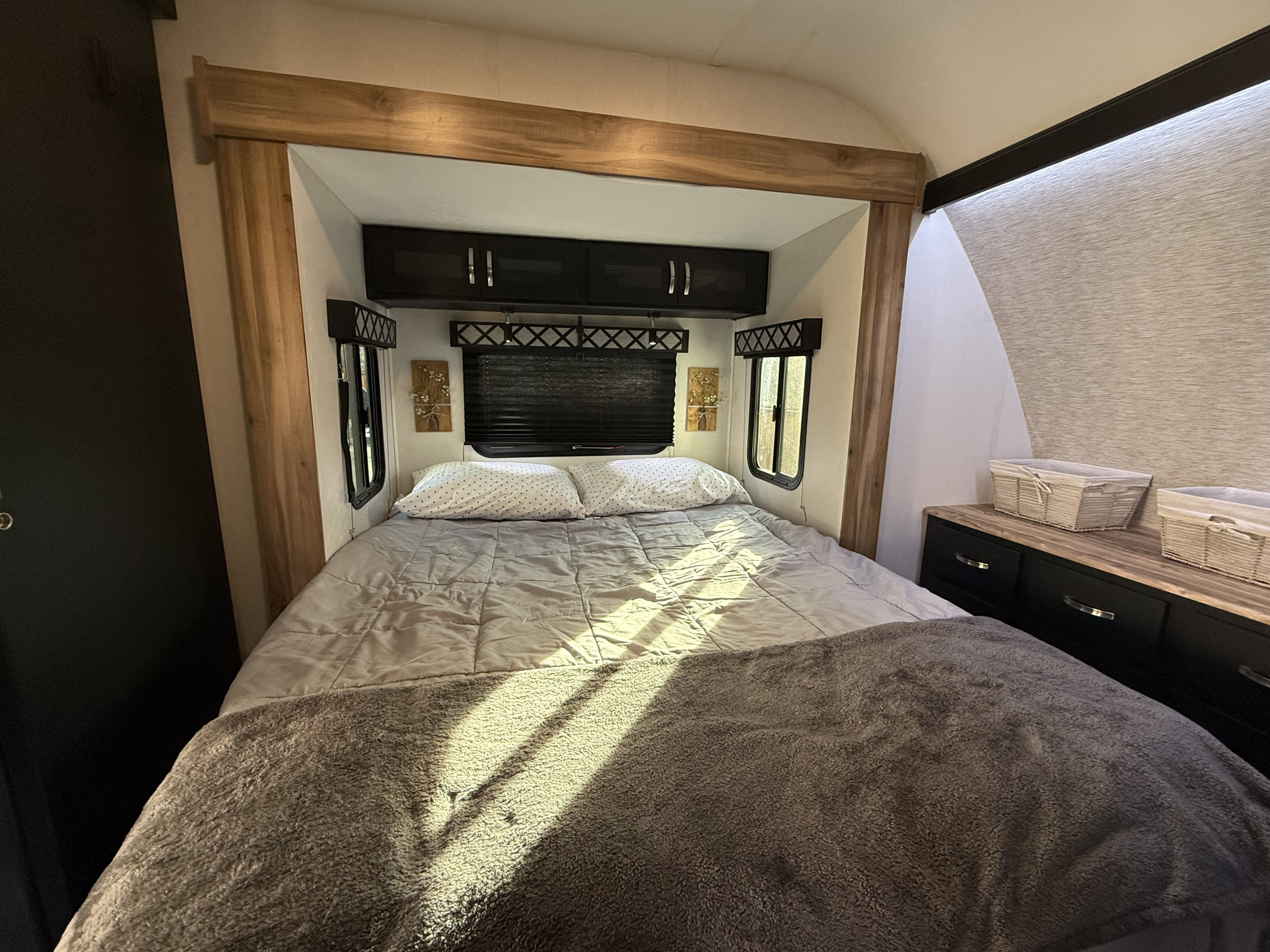 RV rental bedroom: a cozy bed with plush blankets, ample overhead storage, and sunlit windows for a relaxing journey.. Coachmen Adrenaline 2022