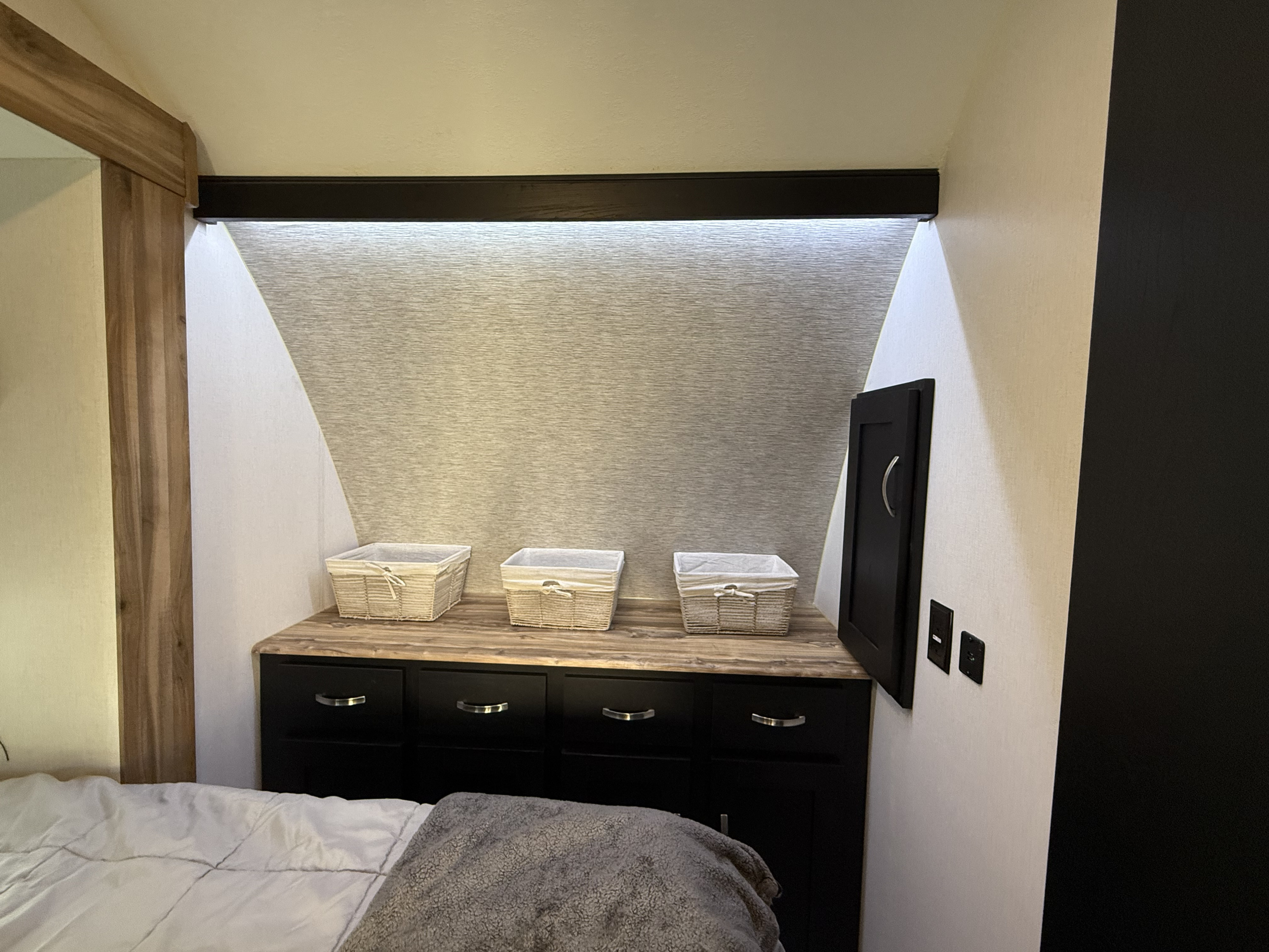 RV rental bedroom showcasing modern built-in storage, textured wall with LED lighting, and warm wood accents.. Coachmen Adrenaline 2022