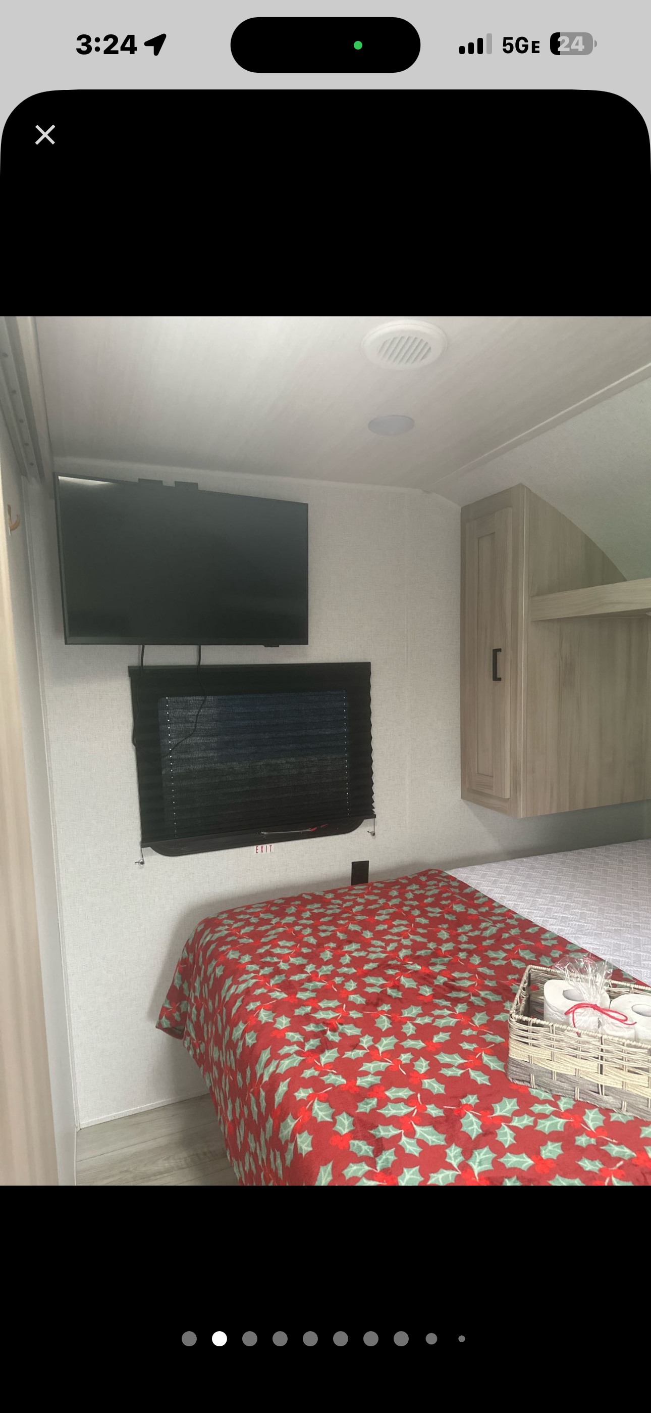 Cozy RV rental bedroom with a wall-mounted TV, window, and bed featuring a festive holly blanket and holiday accents.. East to West Silver Lake 2024