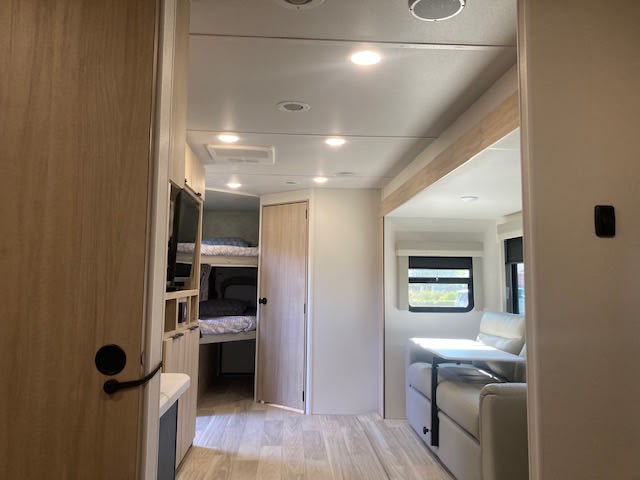 This bright rv rental interior showcases comfortable bunk beds and a living area with a dinette, ideal for your next camper trip.. Winnebago Minnie Winnie 2024
