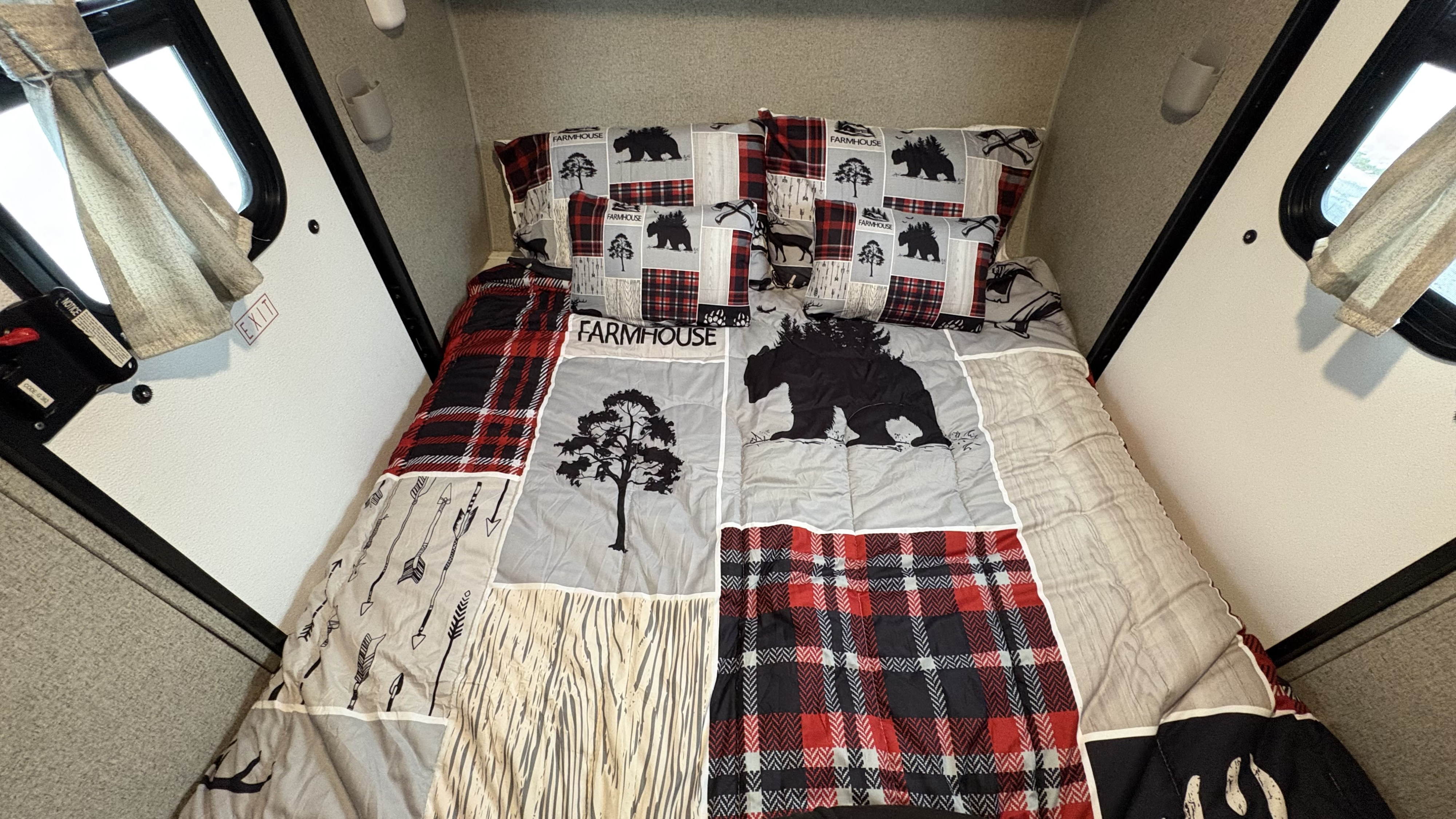 Cozy RV rental bed with rustic bear, tree, and plaid bedding. Ready for adventure and restful nights on the road!. Forest River Rockwood Geo Pro 2018