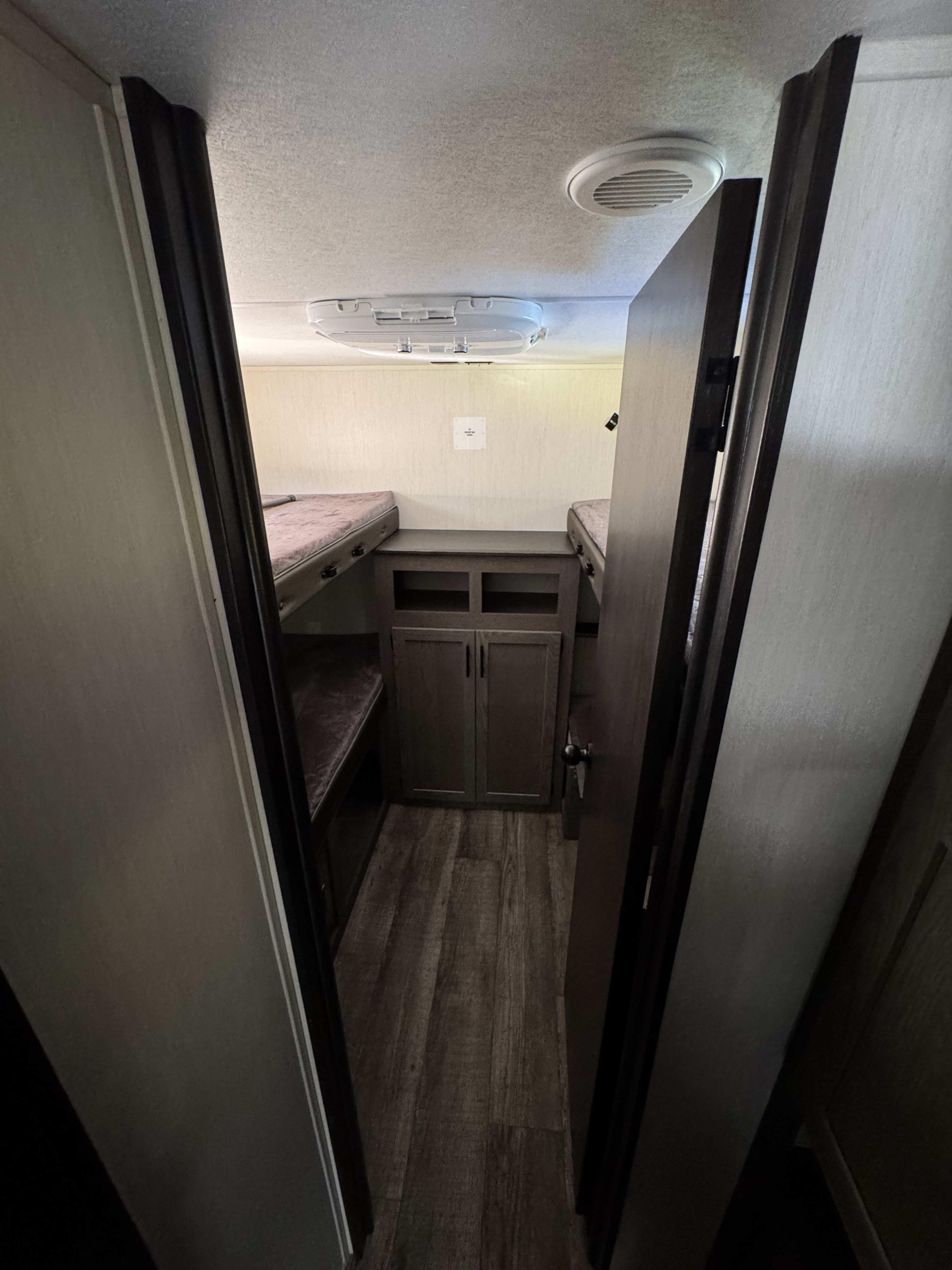 RV rental bunk area with two bunk beds, a central cabinet, and ceiling AC/vents. Ideal for family travel.. Forest River Cherokee Alpha Wolf 2025