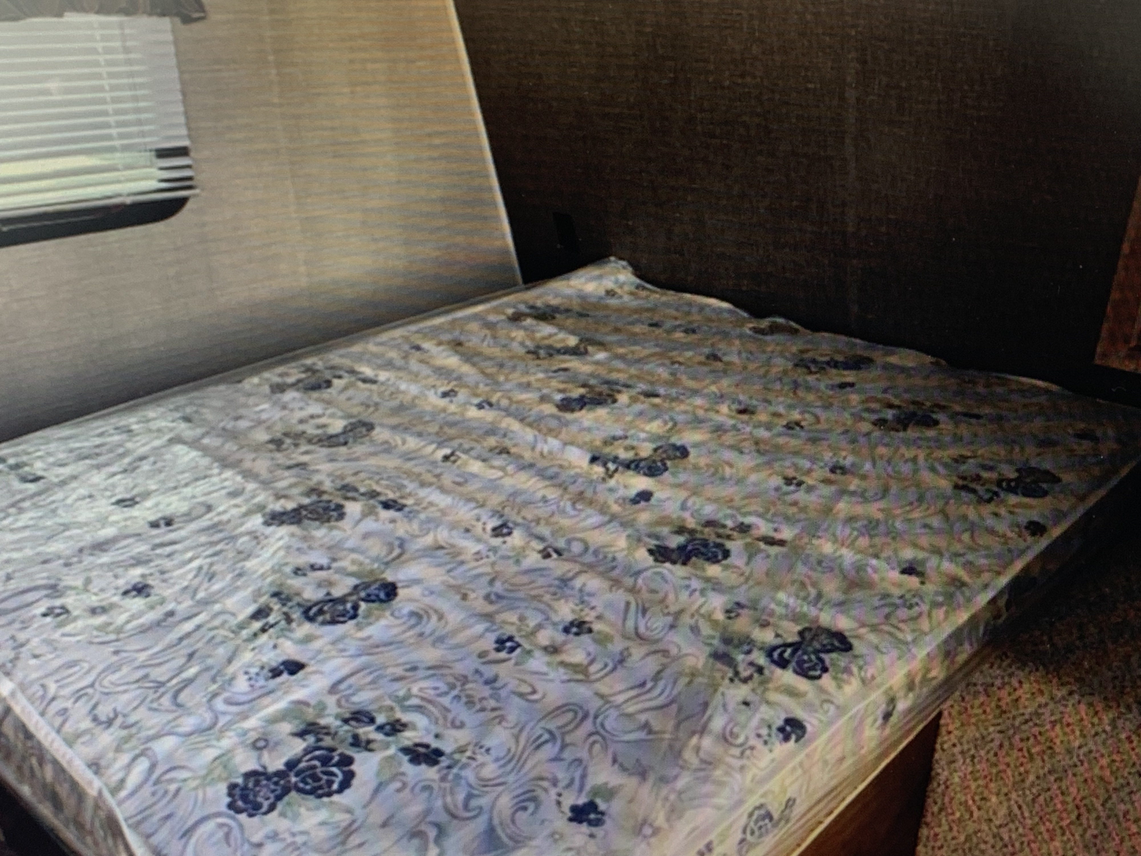 RV rental bedroom: Cozy interior with a patterned mattress, window with blinds, and textured walls, ready for your travels.. Springdale Sumerland mini 2015