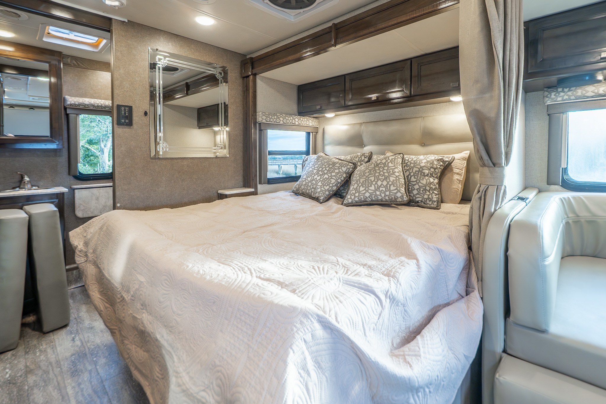 Experience comfort in this RV rental bedroom: large quilted bed, ample storage, private vanity, and scenic window views.. Thor Citation Sprinter 2020