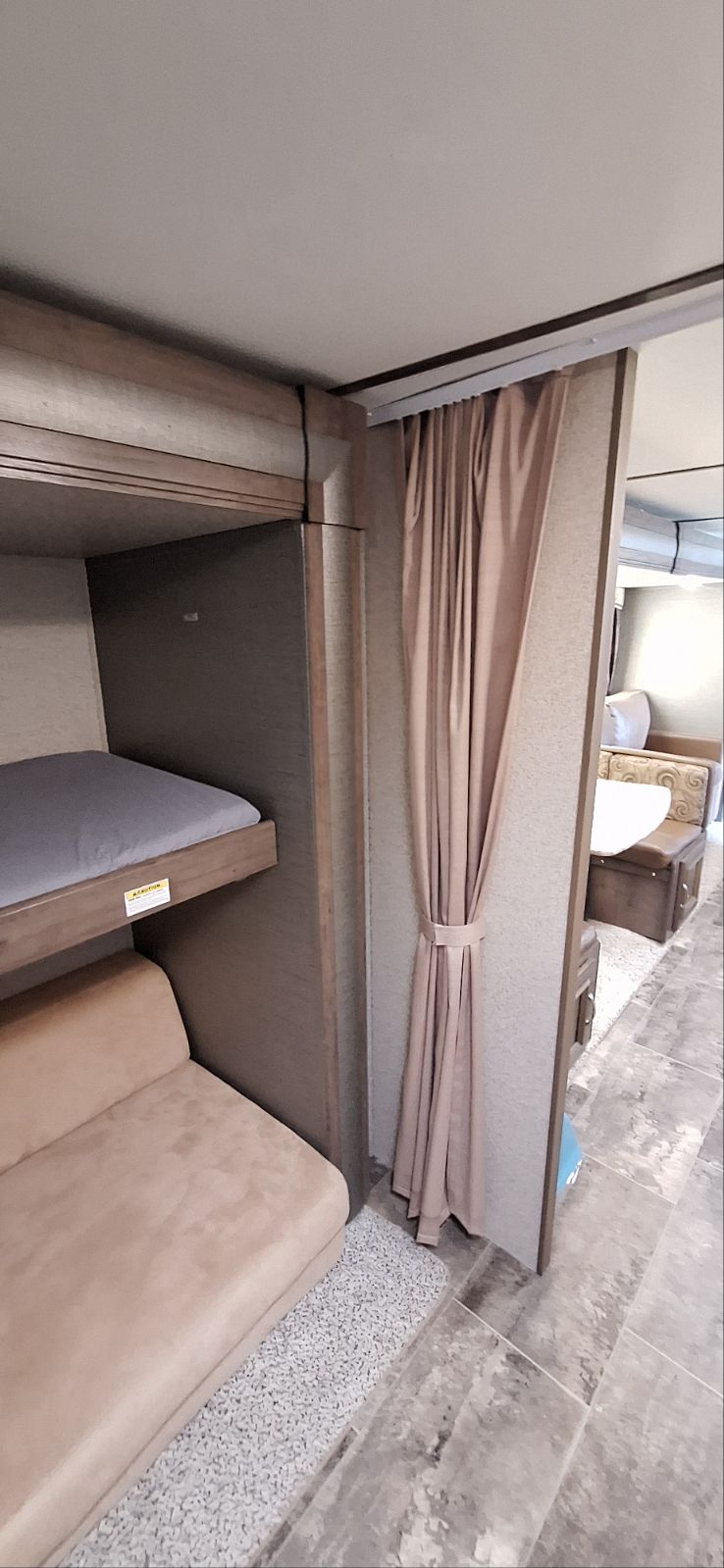 RV rental interior featuring bunk beds, a sofa, and a privacy curtain separating the sleeping area from the dinette.. Passport 3220BH 2018