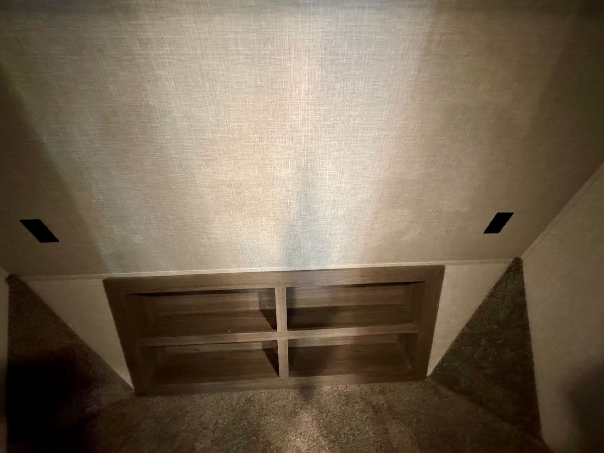 This RV rental interior features a cozy bunk area with built-in wooden shelving, angled carpeted walls, and light textured ceiling.. Crossroads RV Cameo 2021