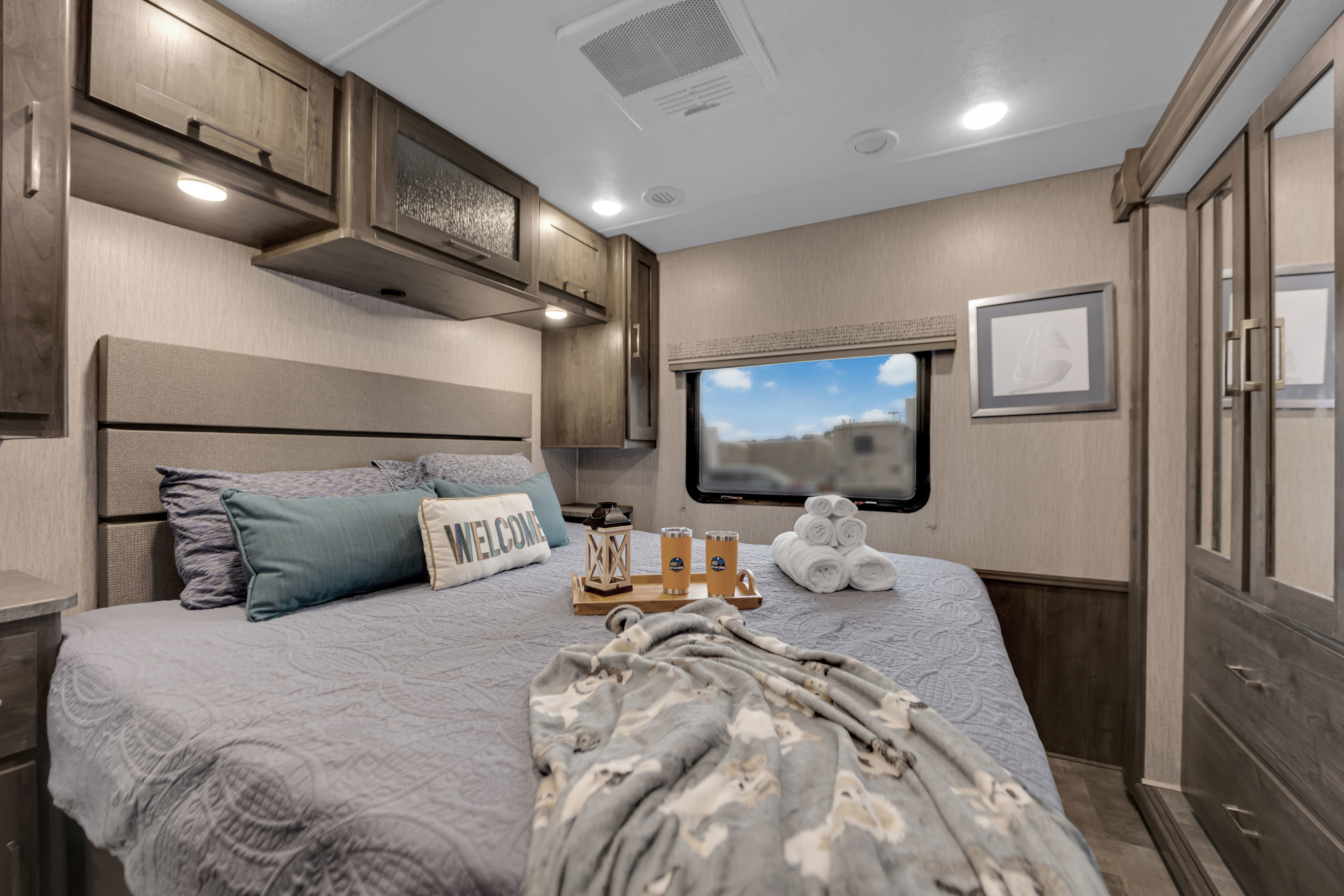 Enjoy this cozy RV rental bedroom with a comfortable bed, welcome pillow, fresh towels, and overhead storage.. Coachmen Pursuit 2022