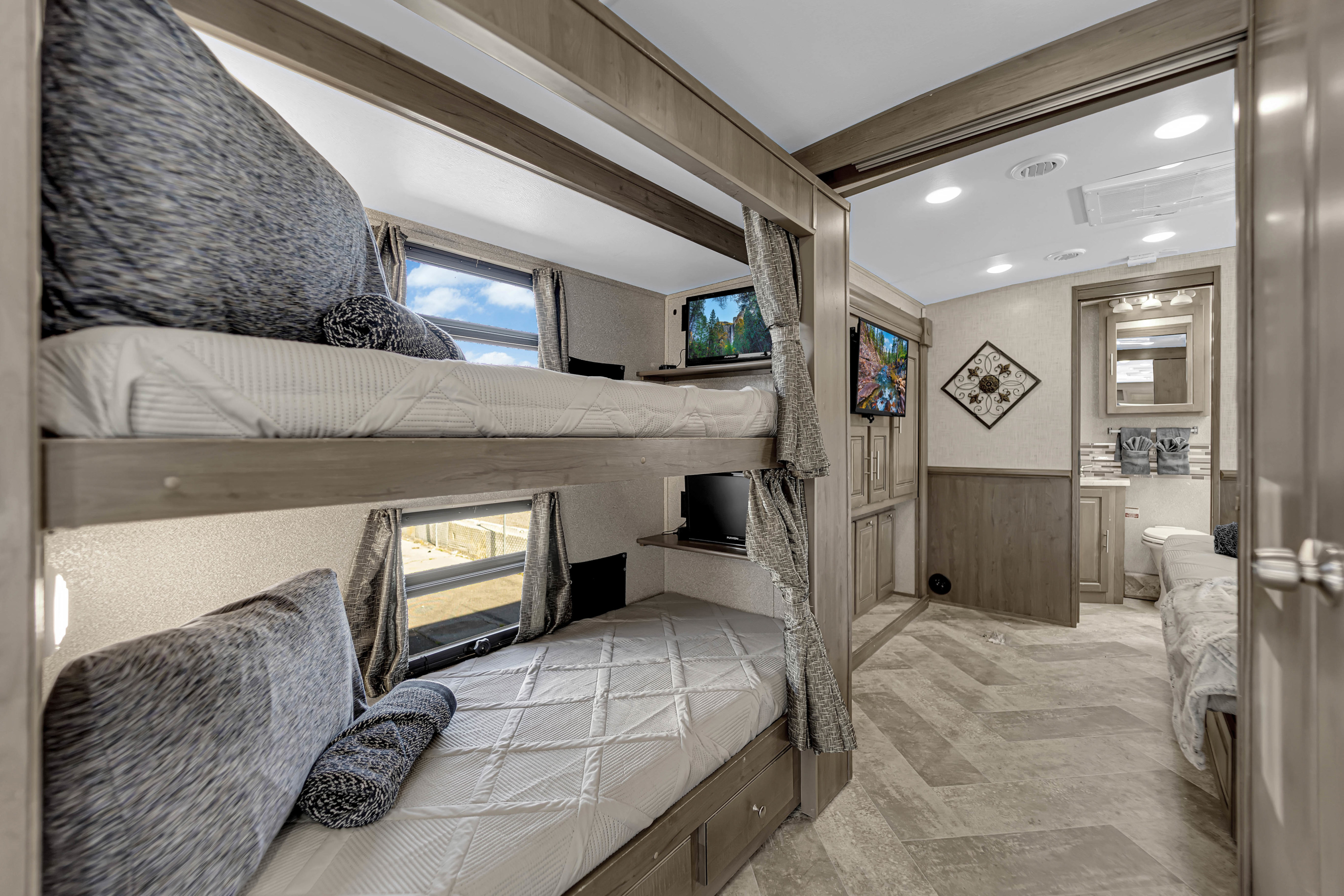Cozy RV rental interior featuring bunk beds with individual TVs, windows, and an adjacent bathroom.. Forest River Georgetown 2019