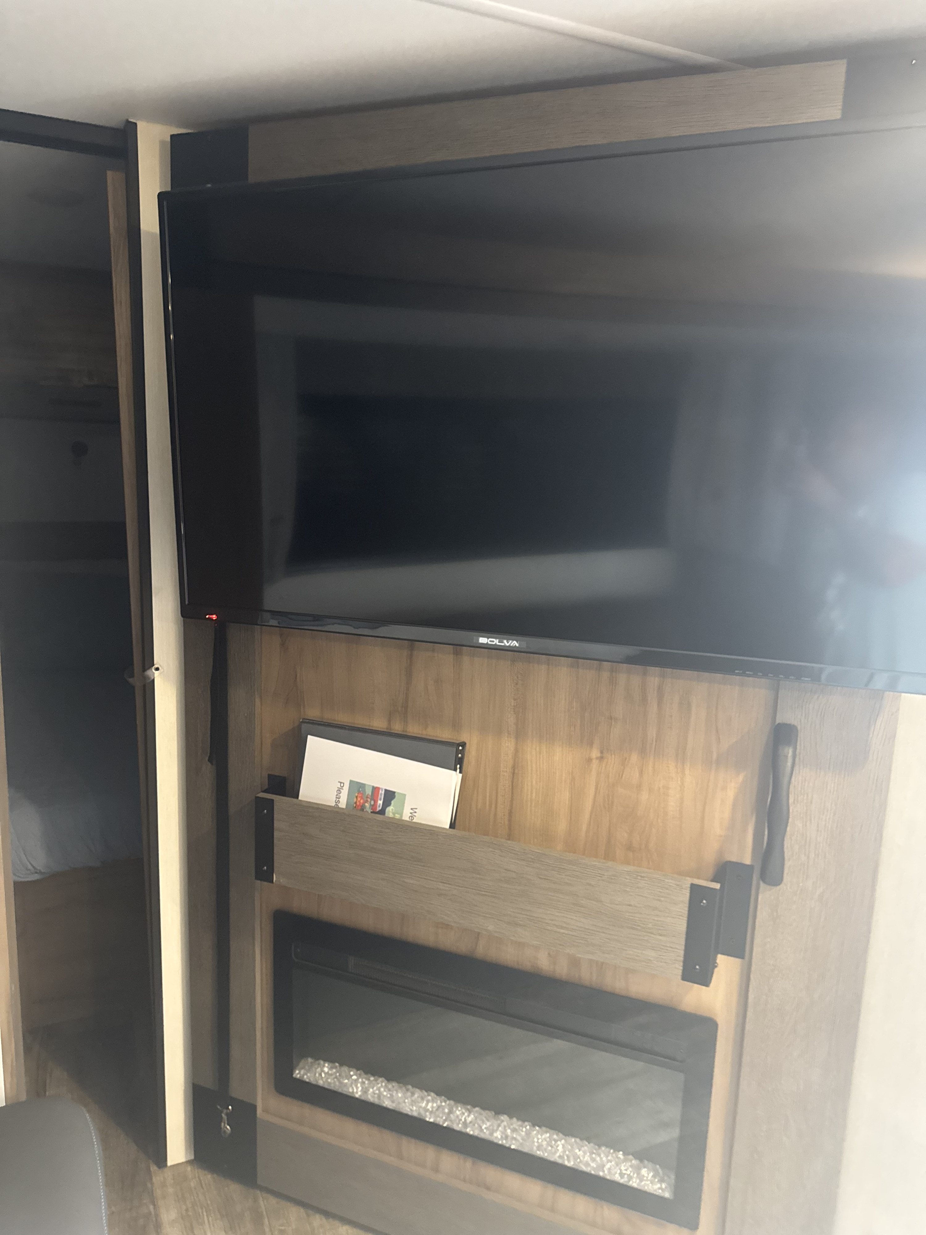 Inside an RV rental: a TV, built-in electric fireplace with decorative crystals, and adjacent bunk beds provide comfort on the go.. Forest River Campsite Reserve 26CJ 2025