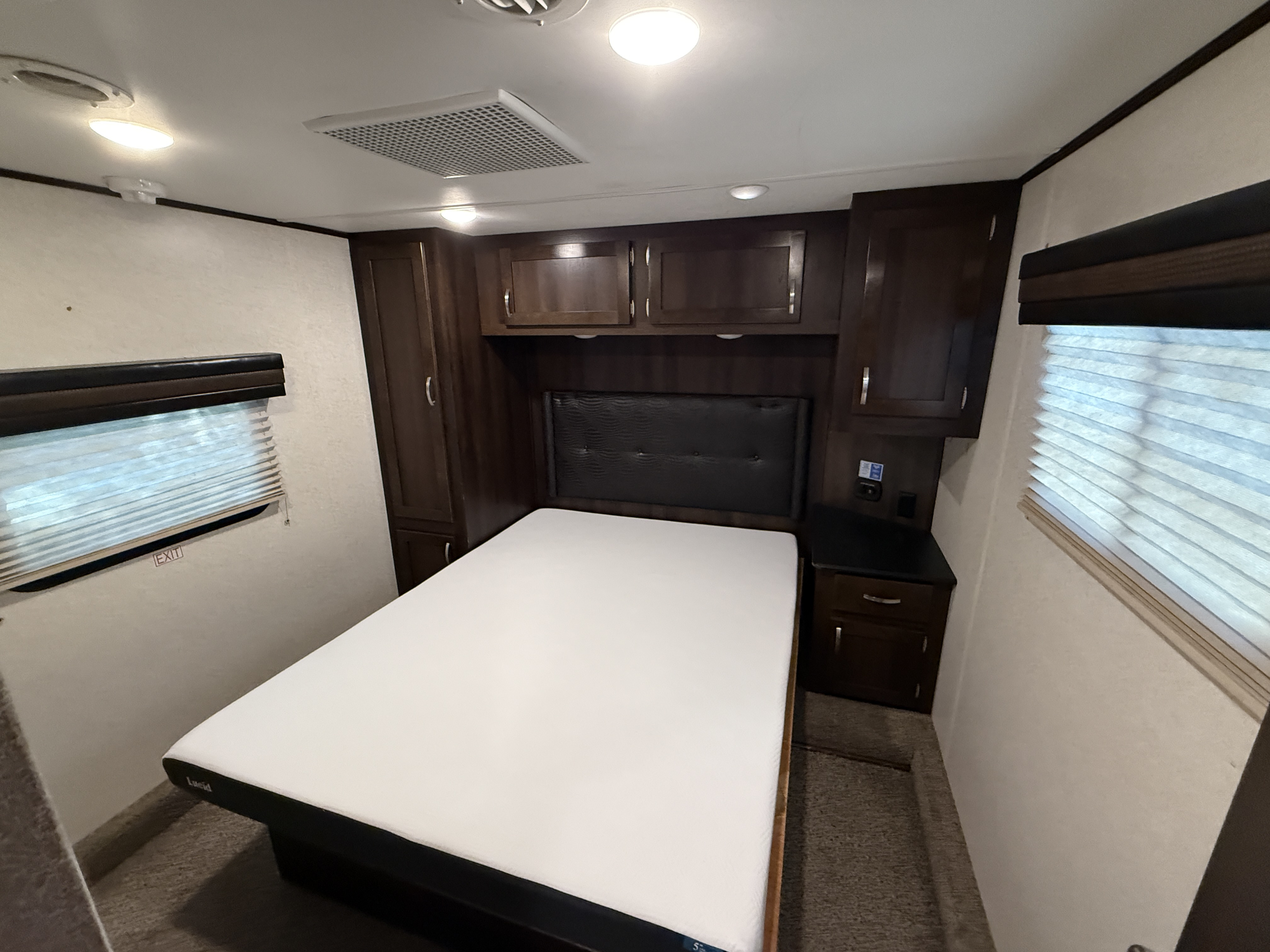 Cozy RV rental bedroom featuring a fresh white mattress, dark wood cabinetry, and lighting for comfortable travels.. Jayco Talon 413TJ18B 2018