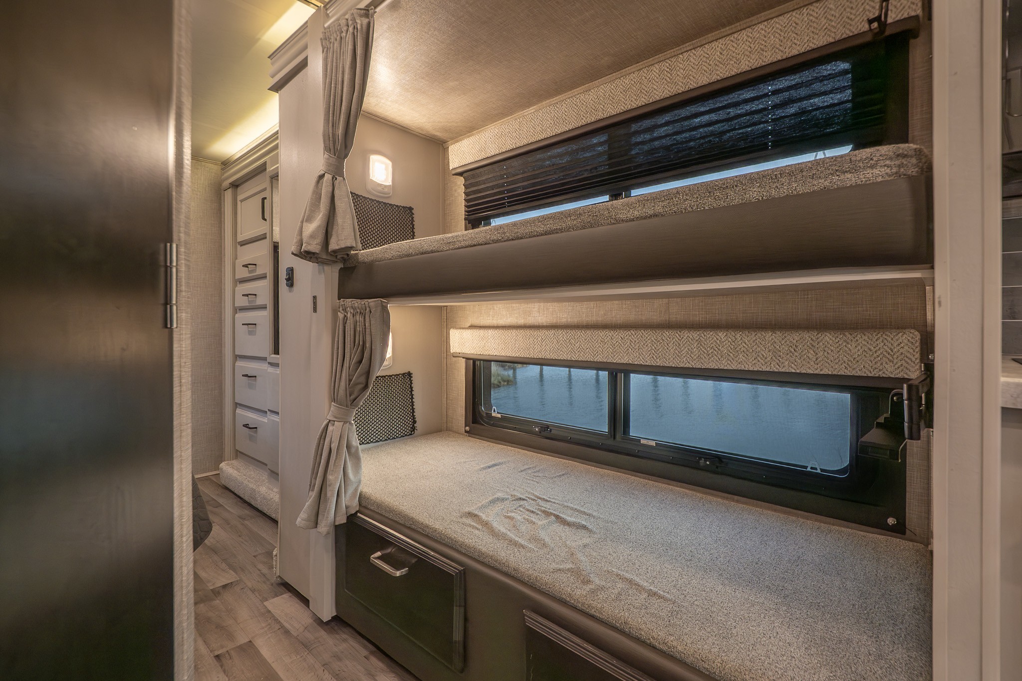 Inside an RV rental: Dual bunk beds with windows and curtains provide compact, comfortable sleeping. Perfect for family travel.. Entegra Coach Odyssey 2023
