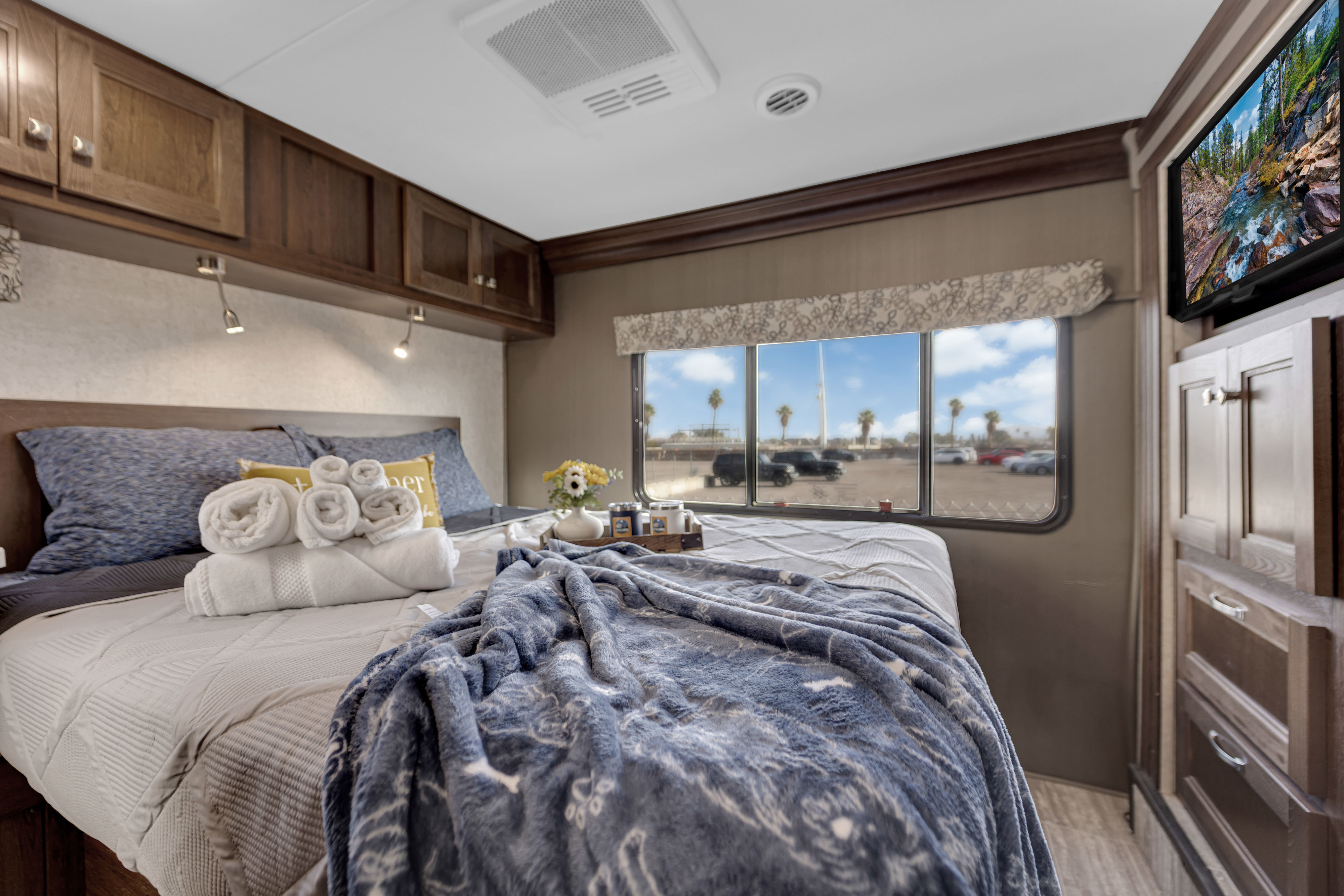Cozy RV rental bedroom featuring a comfortable bed, cabinetry, TV, and a window view, perfect for a relaxing adventure.. Forest River Forester 2020