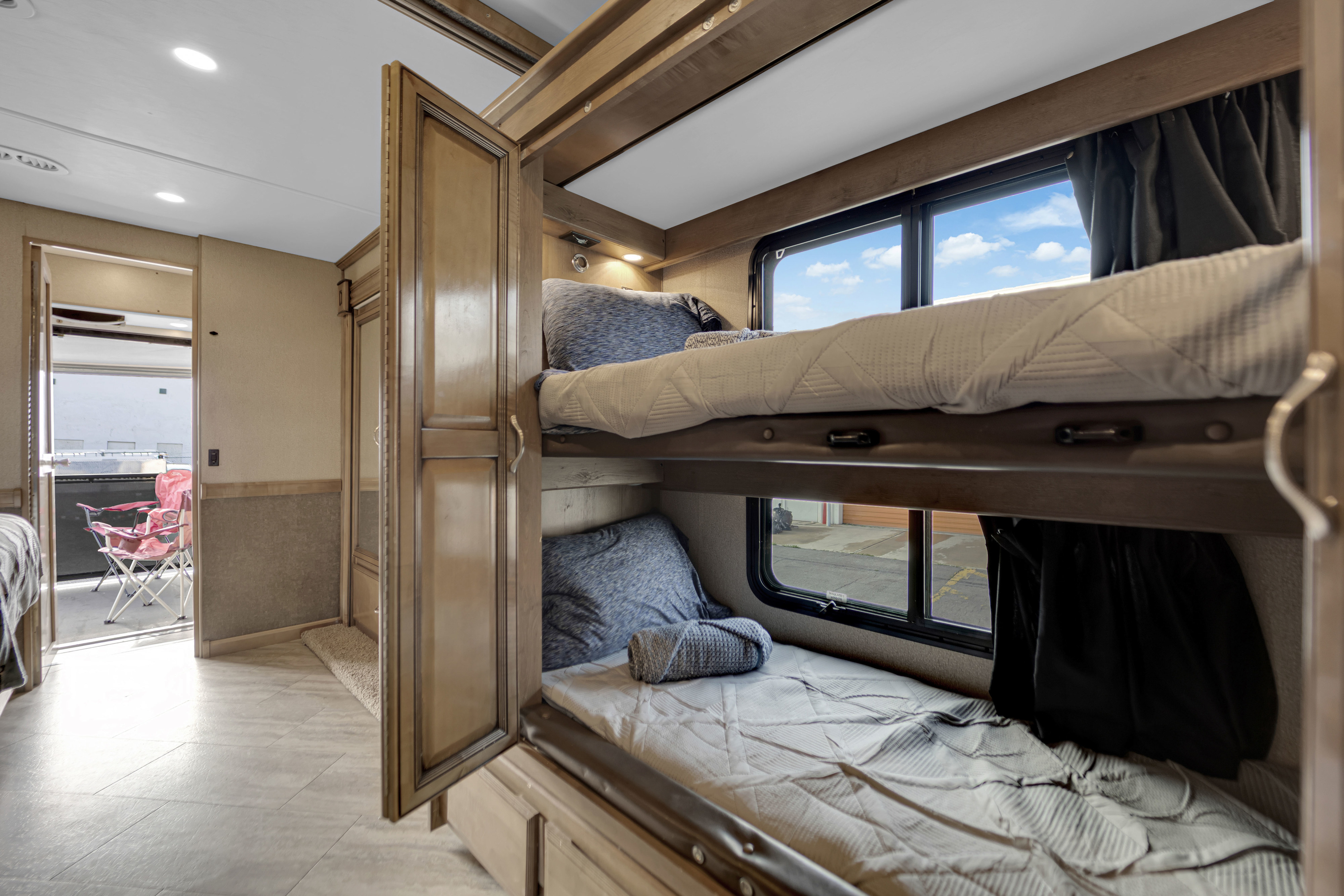 Cozy bunk beds in an RV rental, offering comfortable sleeping and bright windows with scenic views, perfect for travel.. Fleetwood Bounder 2019