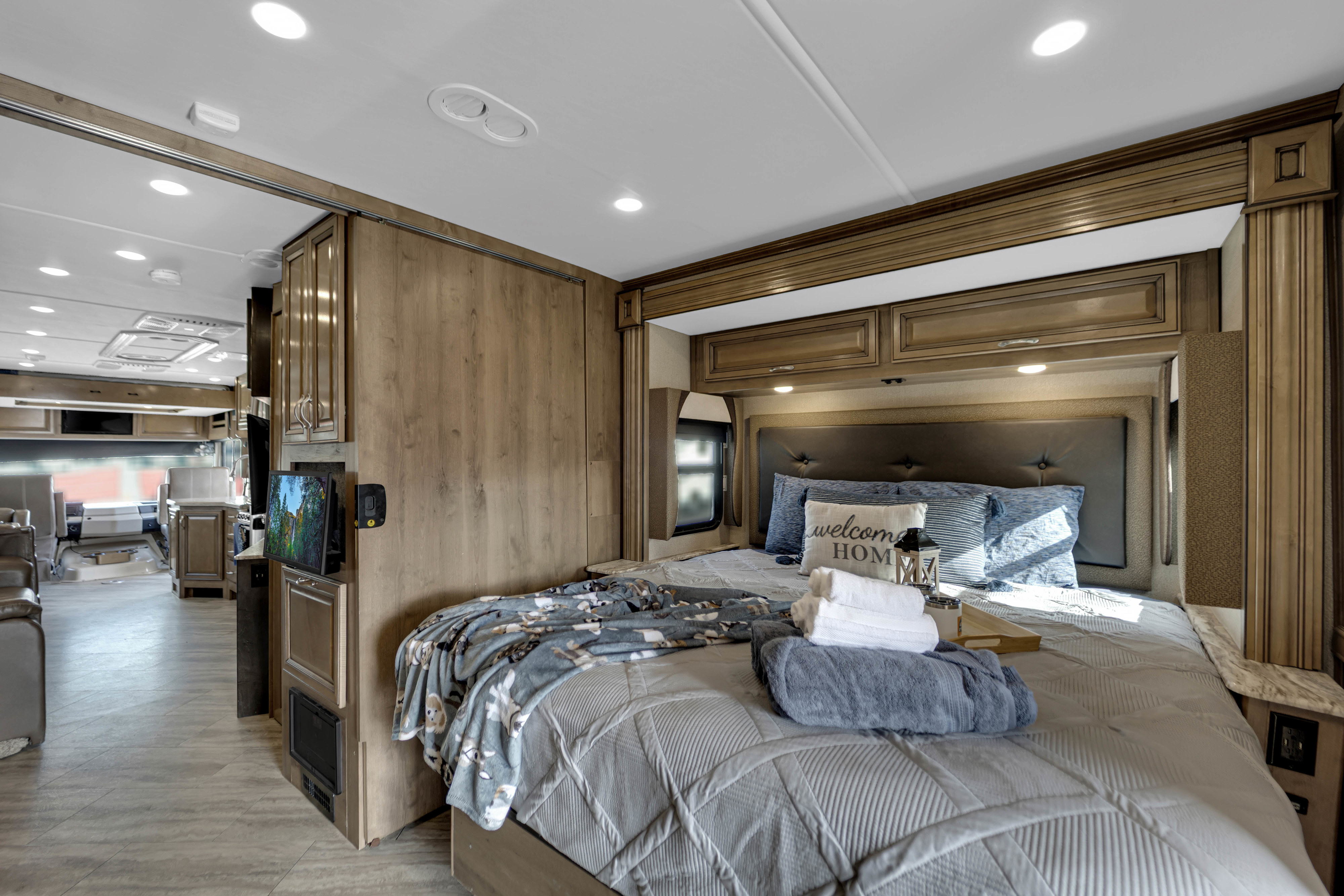 Spacious RV rental bedroom features a cozy bed, stylish decor, and mounted TV. Perfect for a comfortable adventure.. Fleetwood Bounder 2019