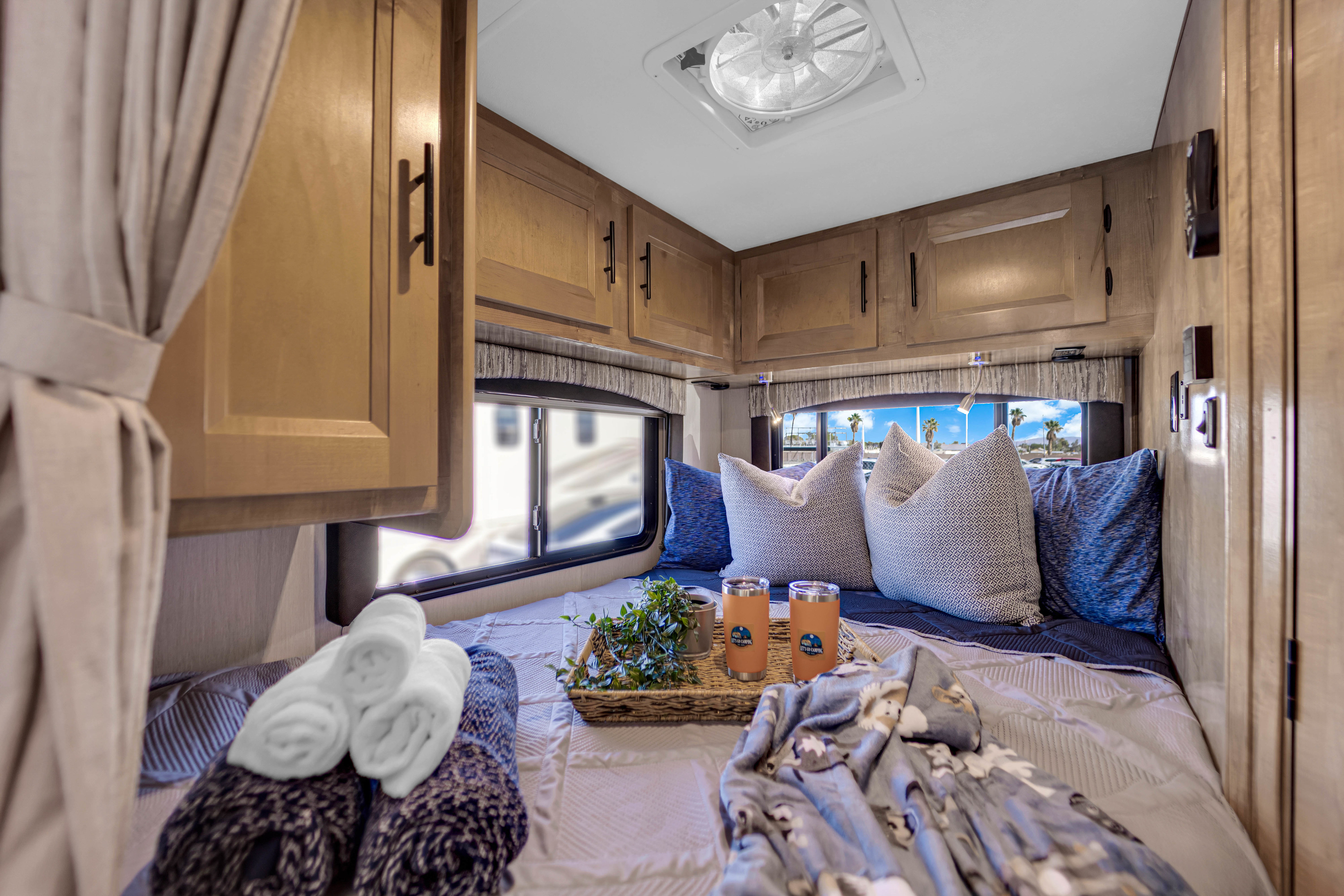 Cozy RV rental bedroom with bed, pillows, window views, and overhead cabinets for a comfortable camping trip.. Coachmen Leprechaun 2021
