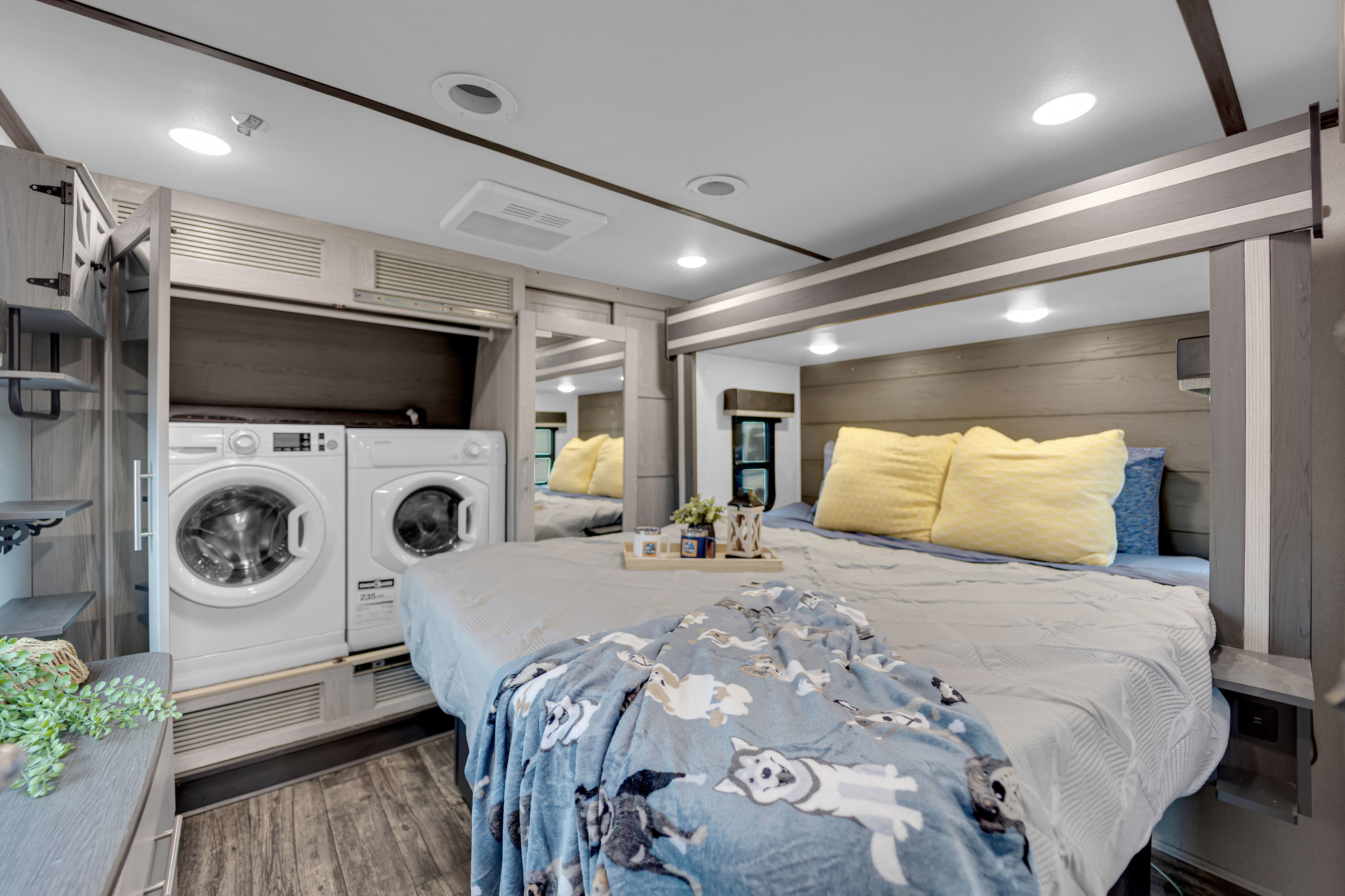 Cozy RV rental bedroom featuring a stacked washer/dryer, plush bed with a dog blanket, and modern decor for travel.. Keystone Fuzion 2022