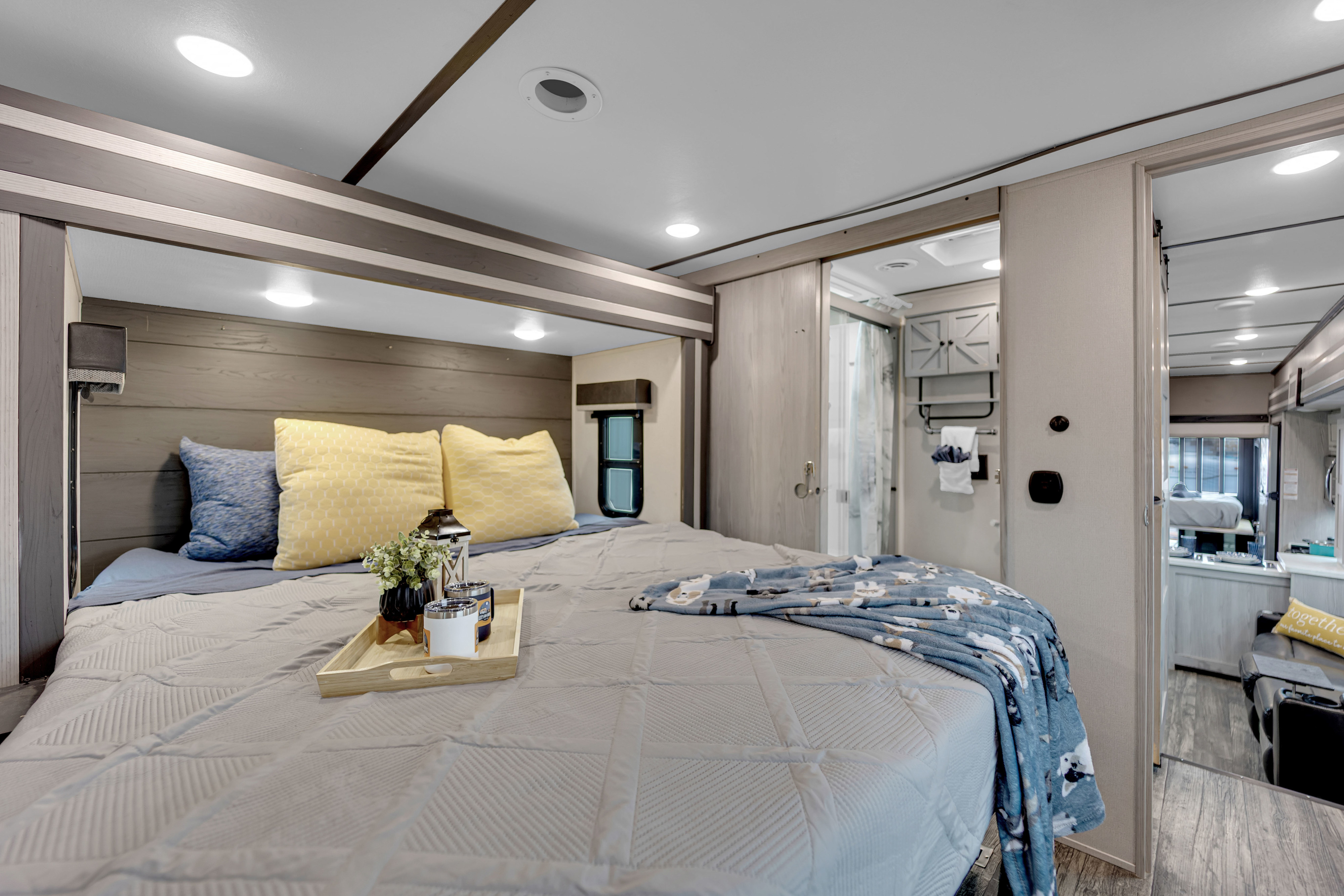 Bright RV rental bedroom: plush bed, patterned blanket, and an en-suite bathroom visible. Ideal for your next adventure.. Keystone Fuzion 2022