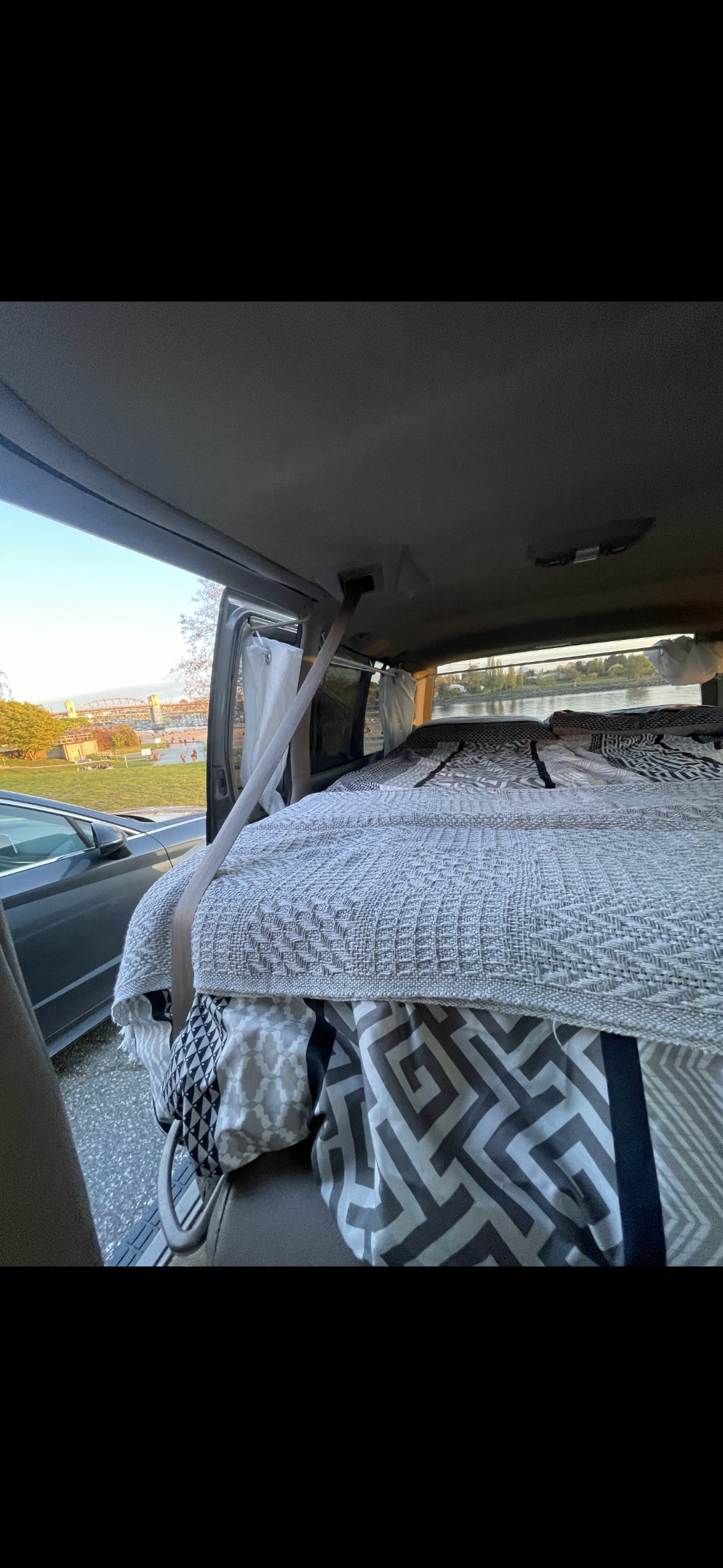 Inside this cozy RV rental: a comfortable bed with scenic water views. Ideal for a relaxing road trip.. Chevrolet Astro 1999