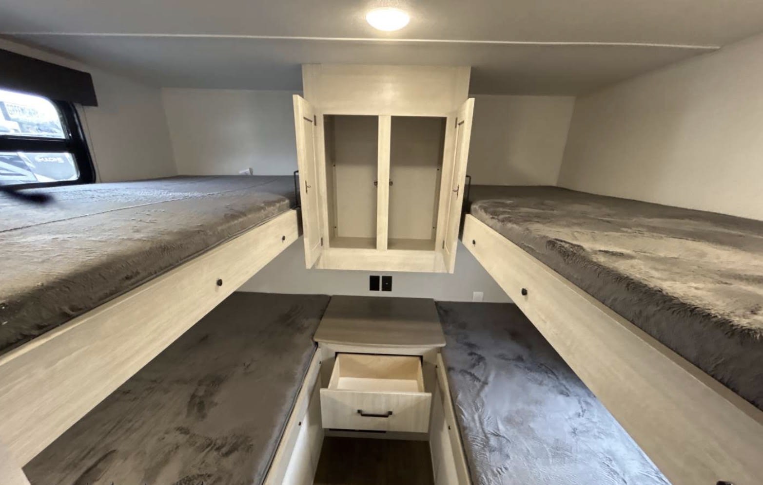 RV rental bunkhouse: 4 beds with grey bedding, central open cabinet, and pull-out drawer. Ideal for family trips!. Forest River Palomino Puma Camping Edition 2025